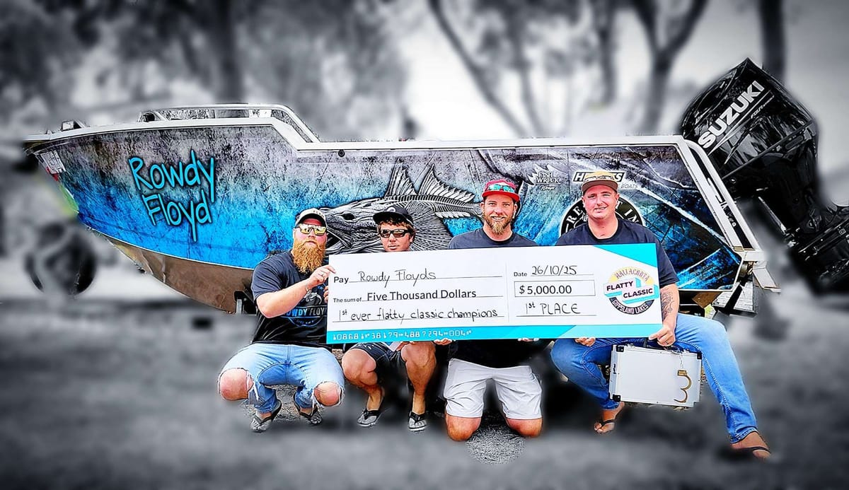 The crew kneeling with the winners' cheque in front of the Rowdy Floyd wrapped boat