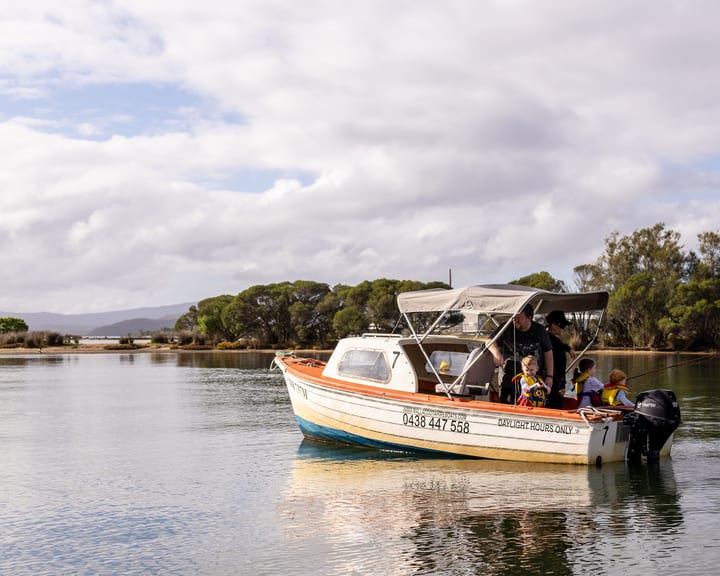 Hire boat 7 drifting near a tree-lined island with a family fishing aboard under a big sky