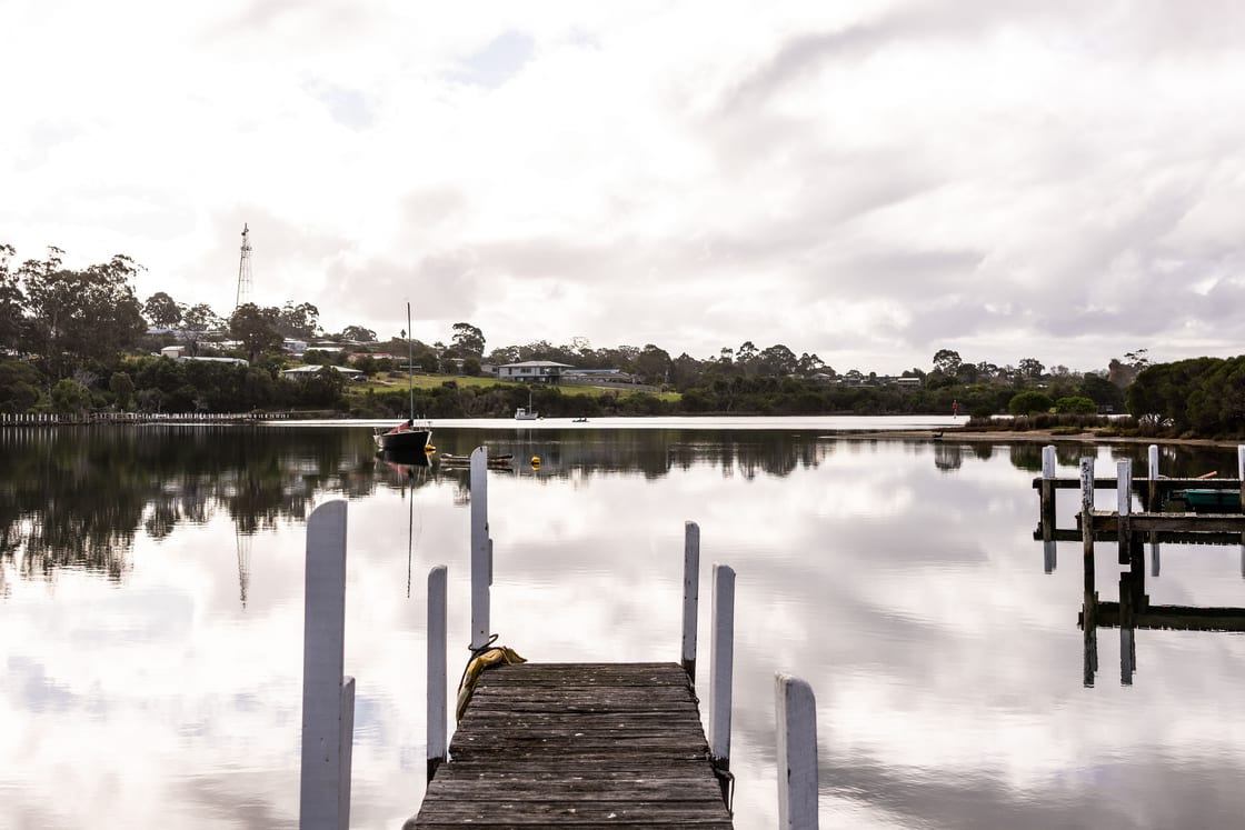 A glassy, still inlet seen from the jetty with mirror reflections at dusk