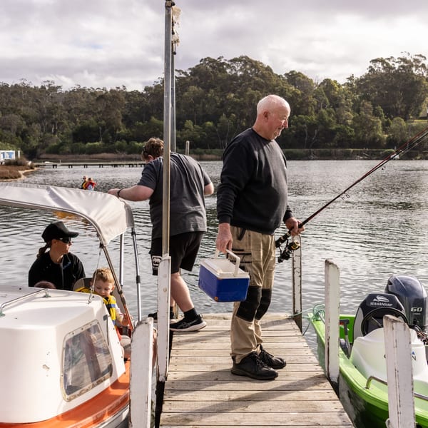 Grant carrying rods and a tackle box down the jetty to a family waiting in their hire boat