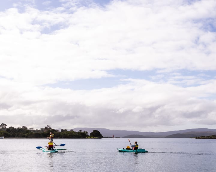 Two kayakers dwarfed by a huge cloudy sky over the Mallacoota inlet
