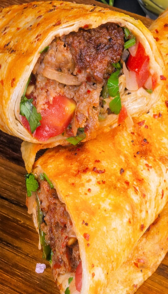 Grilled kofta sandwich with fresh vegetables wrapped in flatbread.