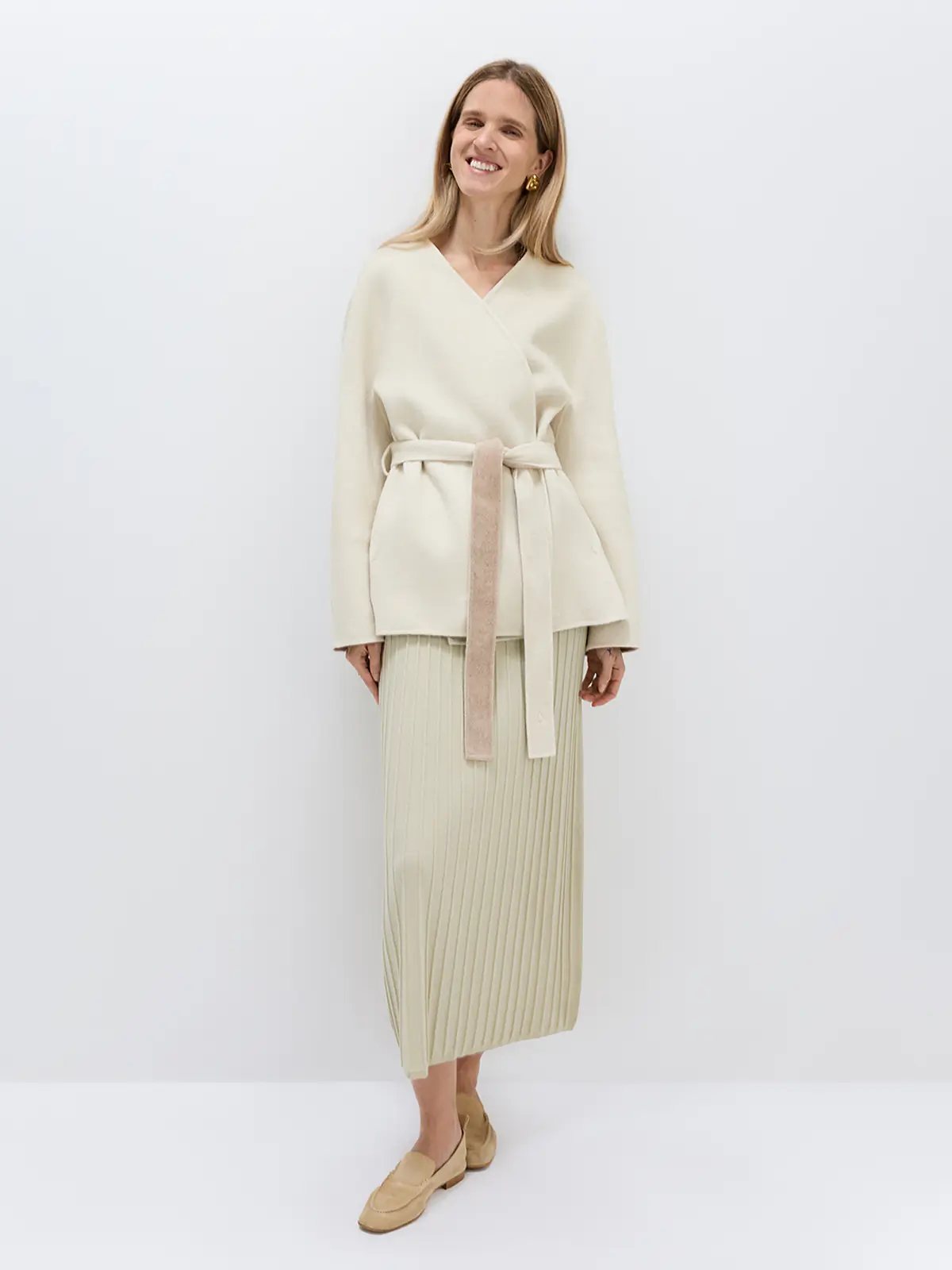 Model wearing an off-white wool lyocell belted coat with a V-neck, wrap front, and self-tie belt.