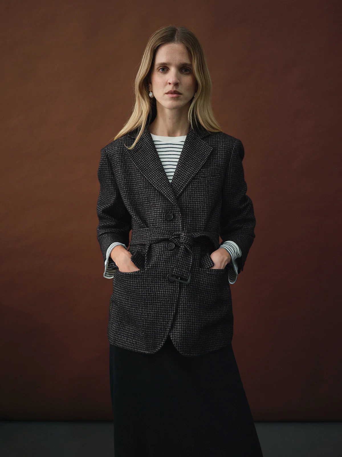 Model in andreatang houndstooth belted blazer over striped top with dark skirt