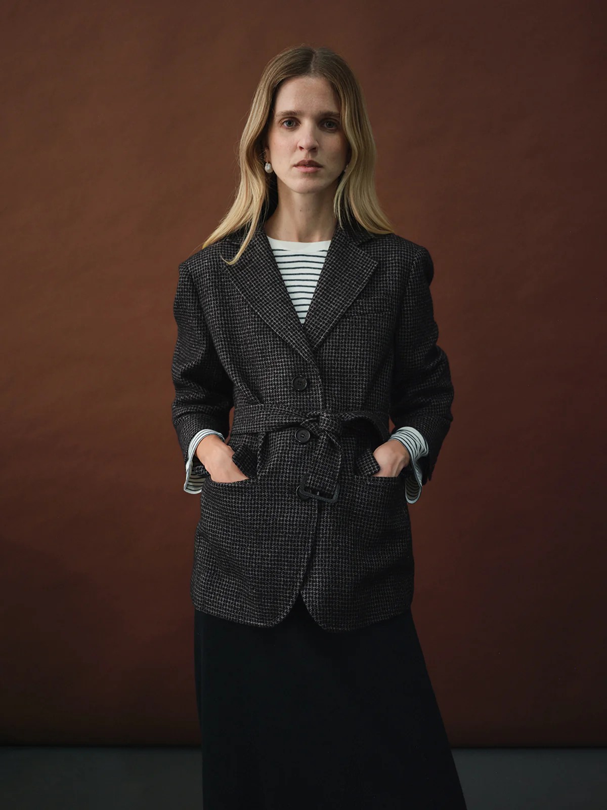 Model in andreatang houndstooth belted blazer over striped top with dark skirt