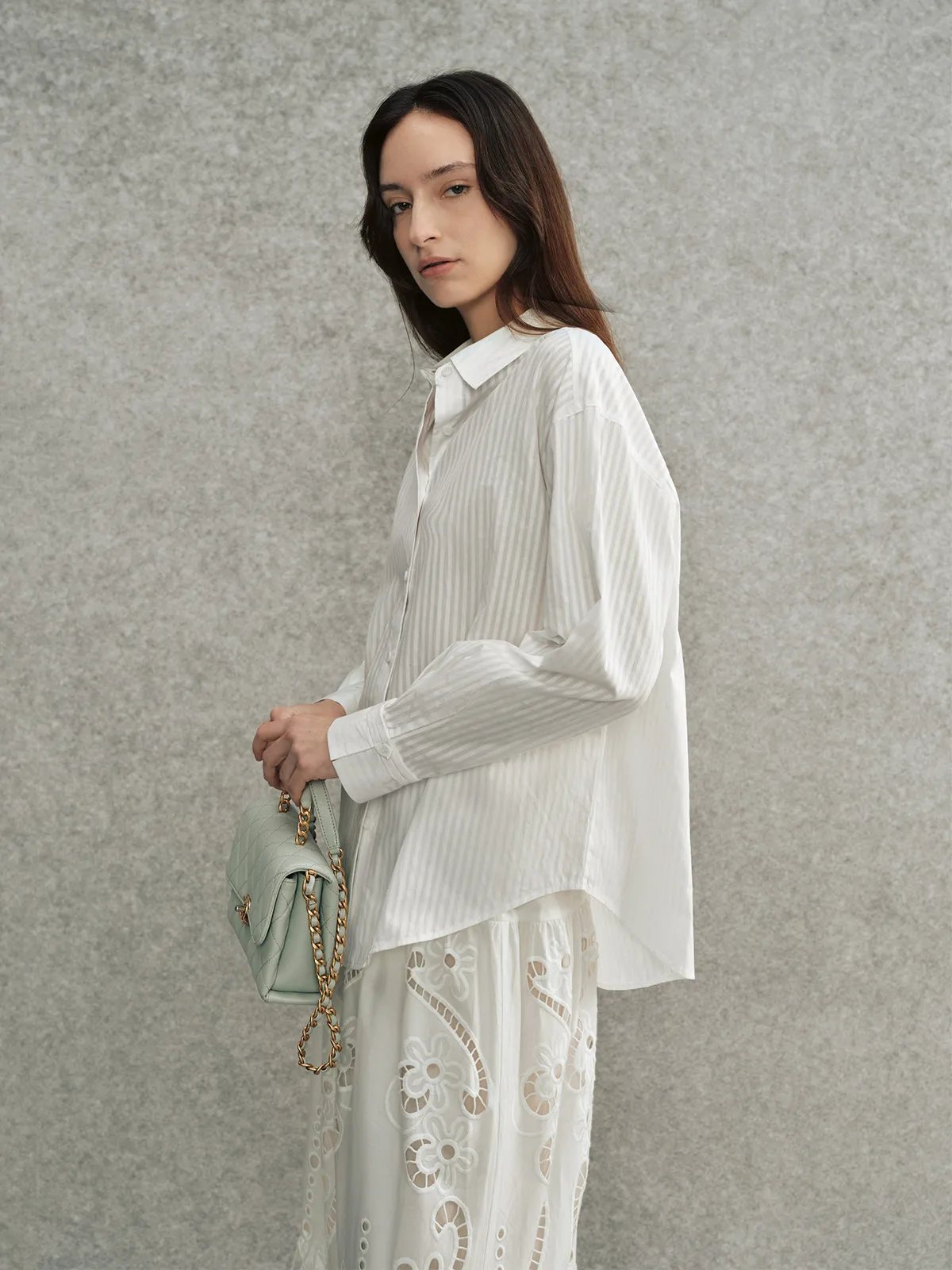 Side profile of model wearing KIARA striped shirt with white eyelet lace skirt and mint bag