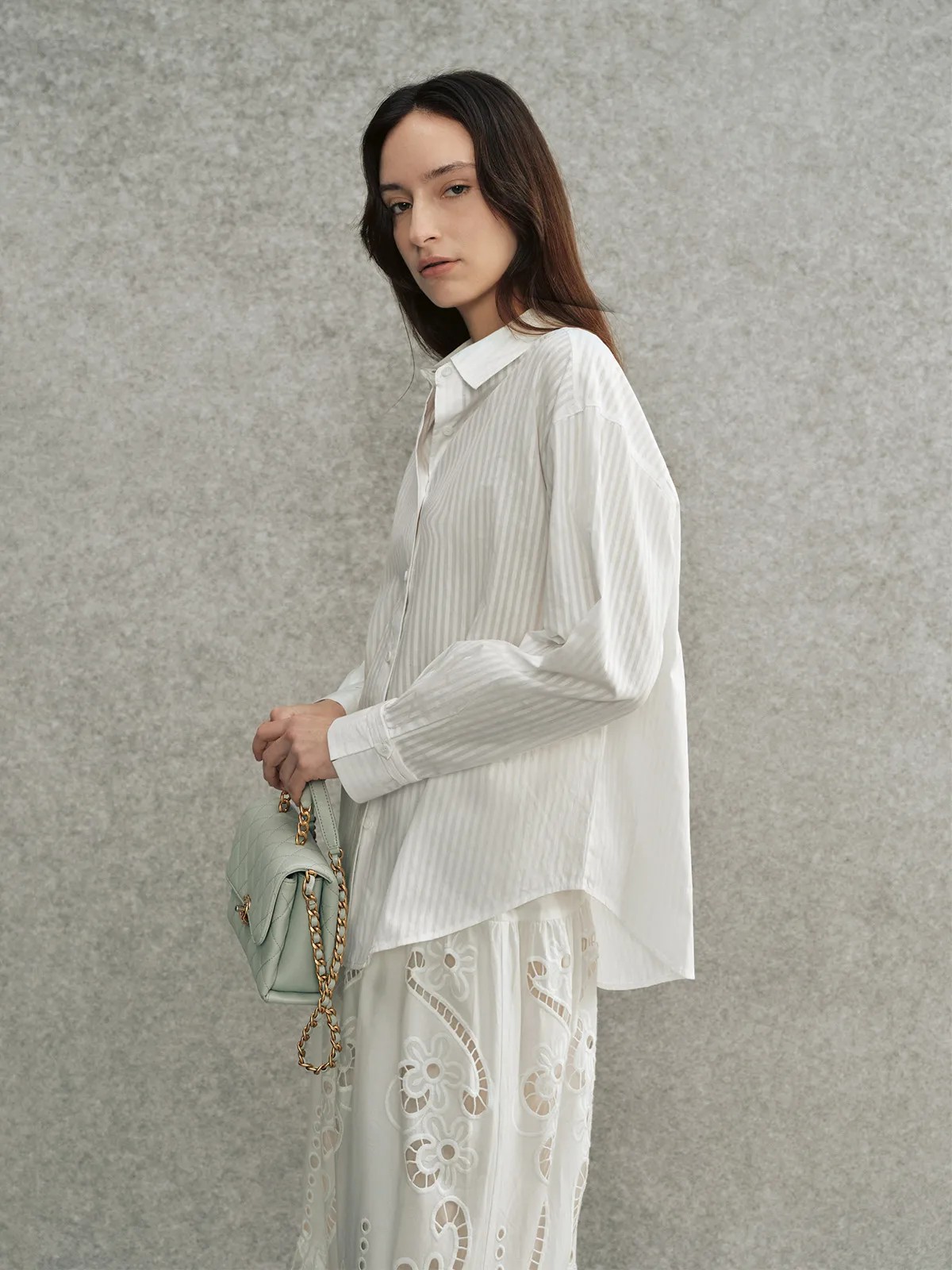 Side profile of model wearing KIARA striped shirt with white eyelet lace skirt and mint bag