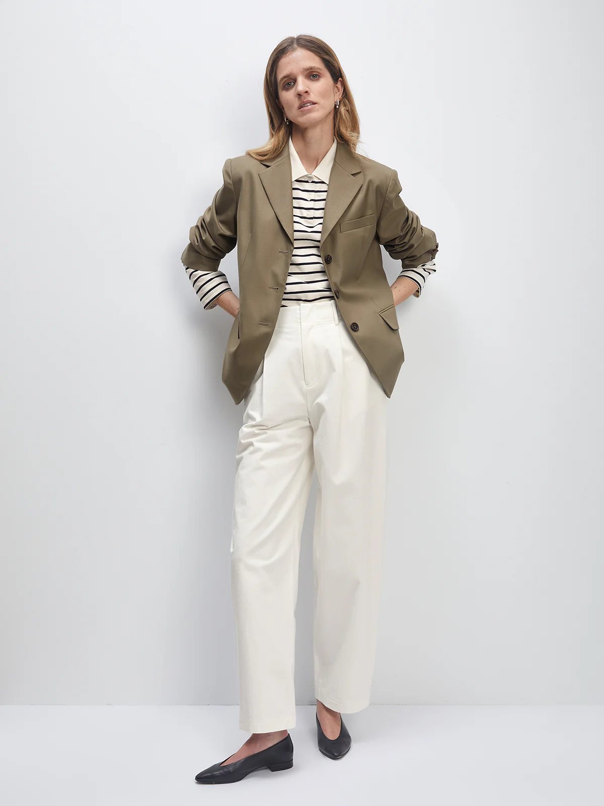 Model wearing the Khaki Green Wool Acetate Cuban-Collar Blazer over a striped shirt and trousers, hands in pockets.