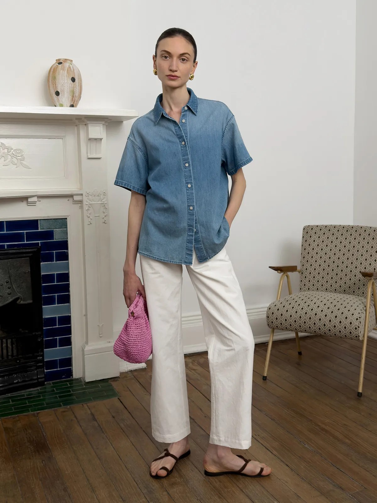 Model wearing DENZEL denim shirt with white wide-leg pants and pink crocheted bag in vintage interior