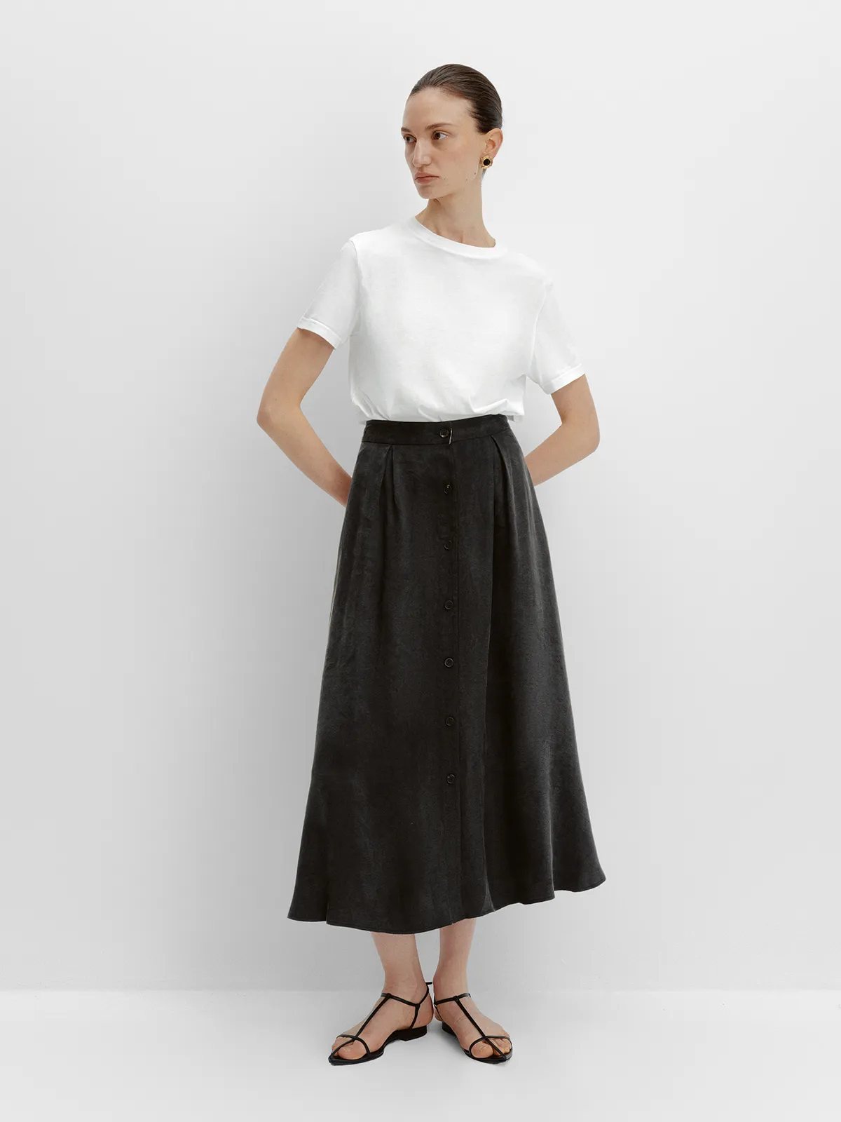 Front full view of black NOBU Midi Skirt with white crew-neck tee and hands on hips
