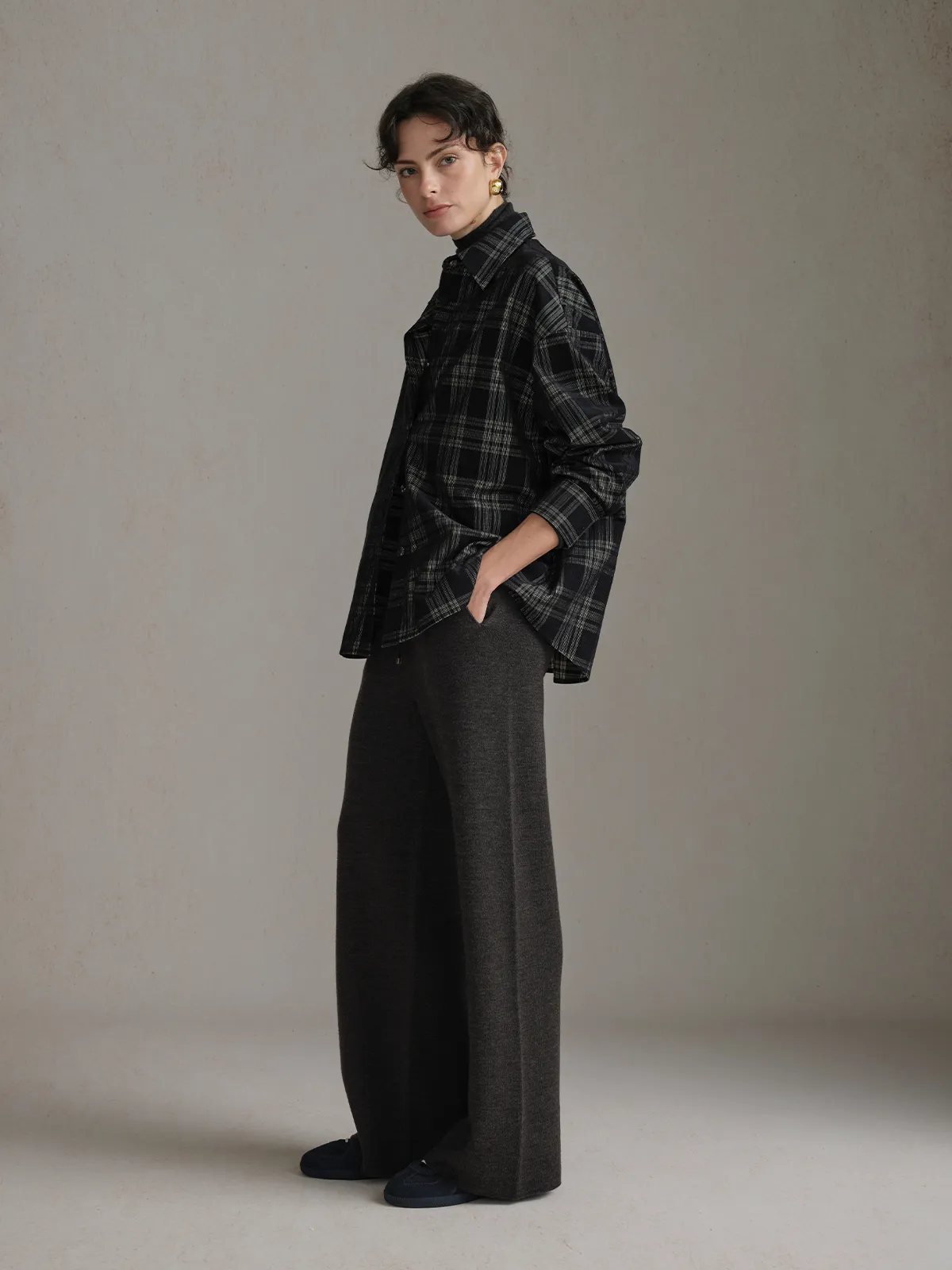 Three-quarter side profile of model wearing ALDER overshirt with hands in pockets, paired with charcoal wide-leg trousers