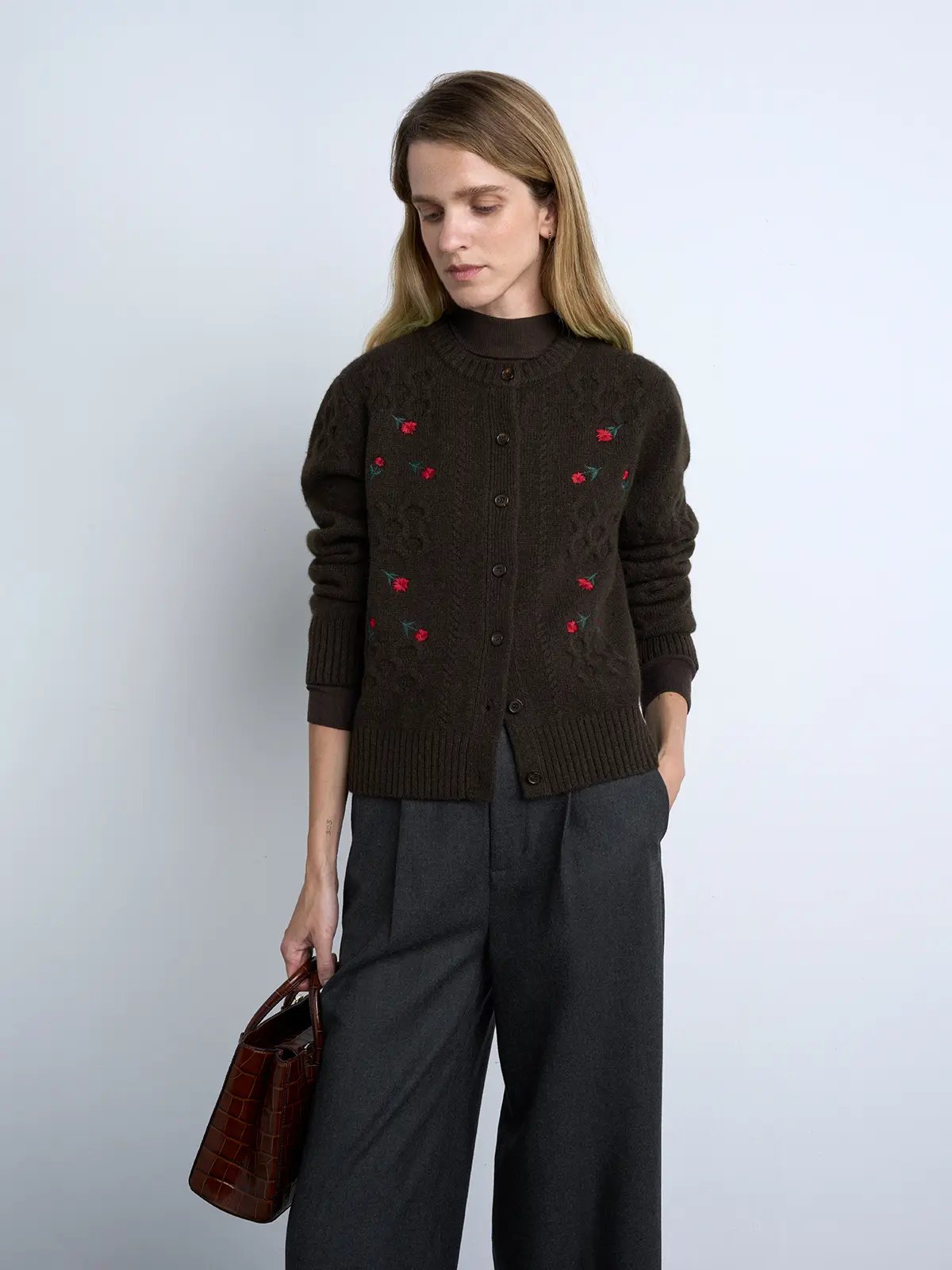 Model wears a Brown yak wool cardigan with floral embroidery, ribbed trim, and button closure over a dark turtleneck.