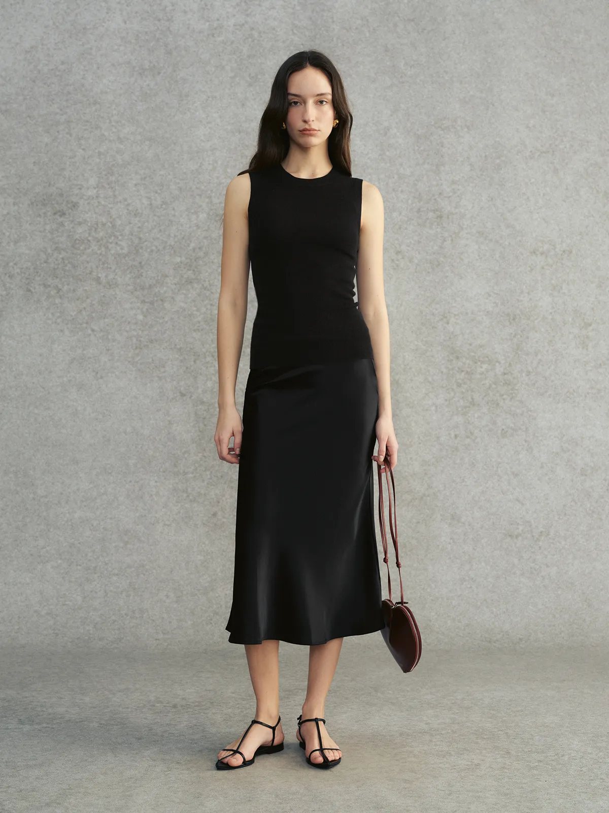 Model wearing black DELIA knit top with black satin midi skirt and strappy sandals
