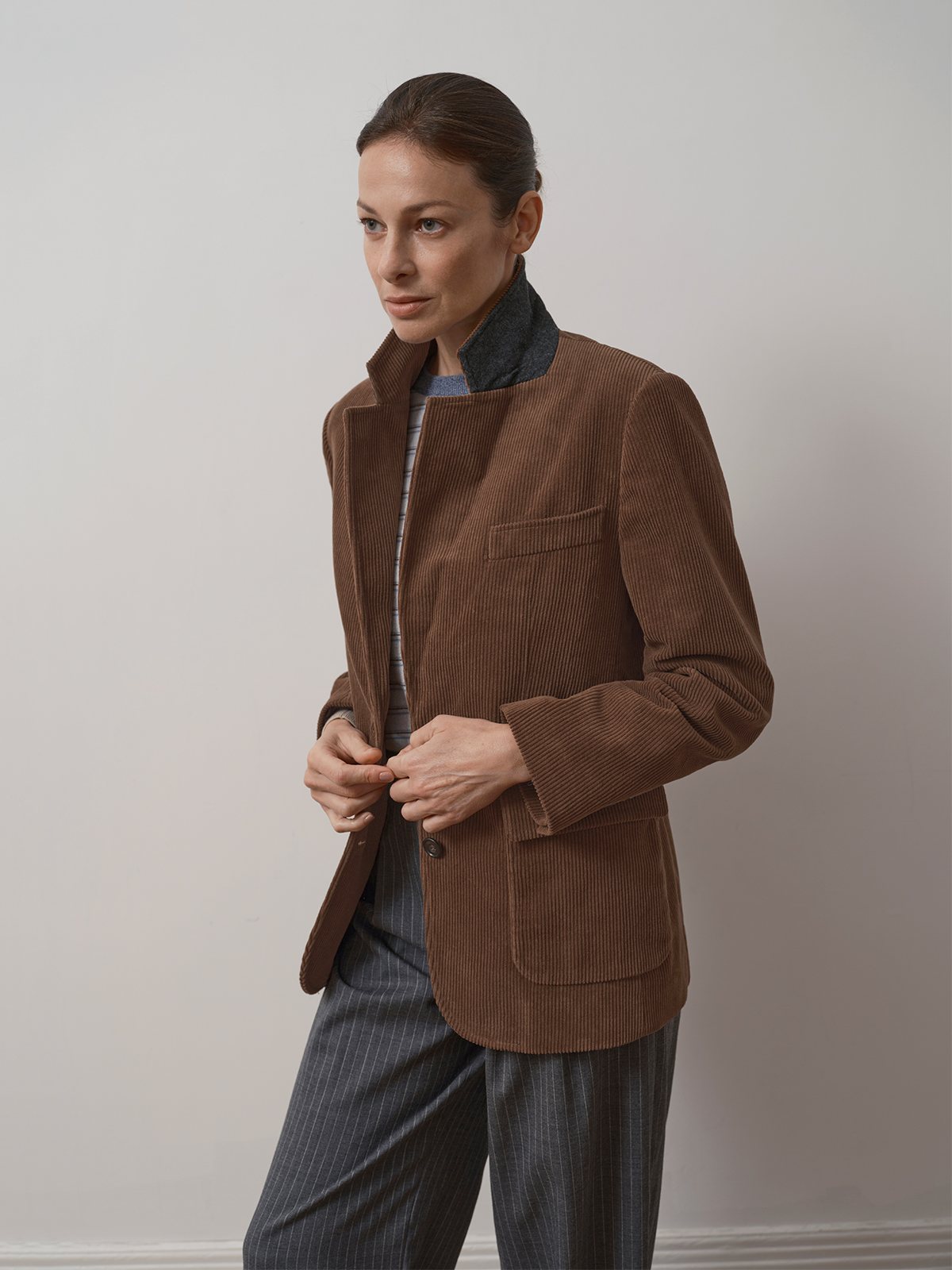 Model adjusting KIMBERLEY blazer front, highlighting collar lining and relaxed sleeve cuff