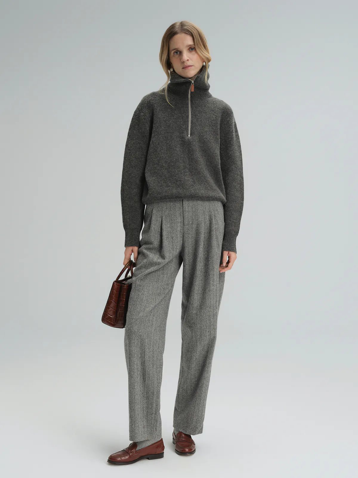 Side view of model wearing Gray wool herringbone tapered trousers with a gray sweater and loafers.