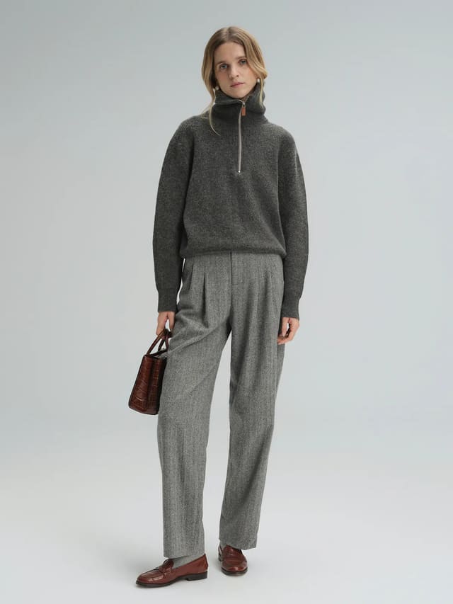 Side view of model wearing Gray wool herringbone tapered trousers with a gray sweater and loafers.