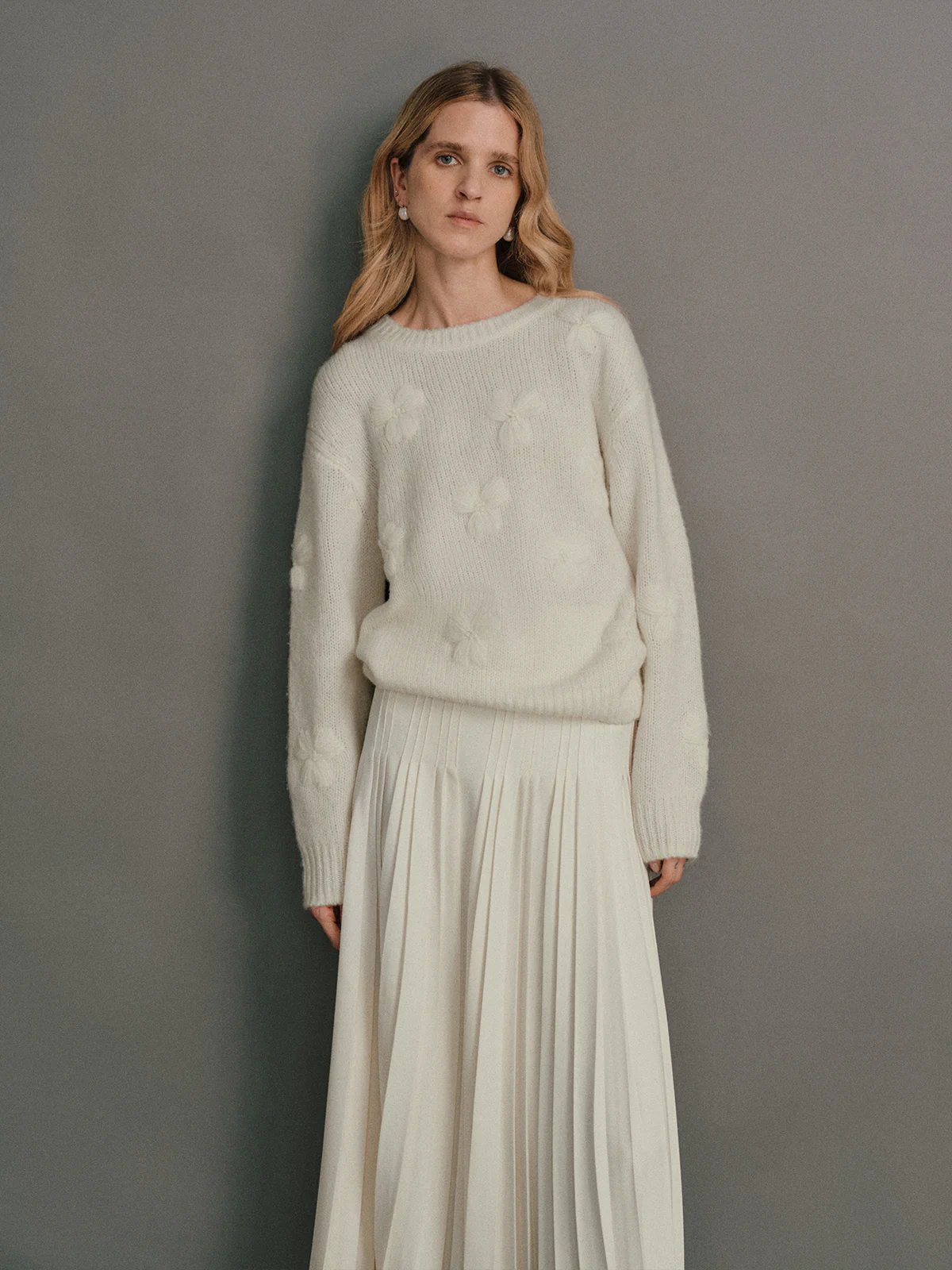 Front view of a model wearing a Pink alpaca wool embroidered jumper with floral motifs and wide-leg jeans.