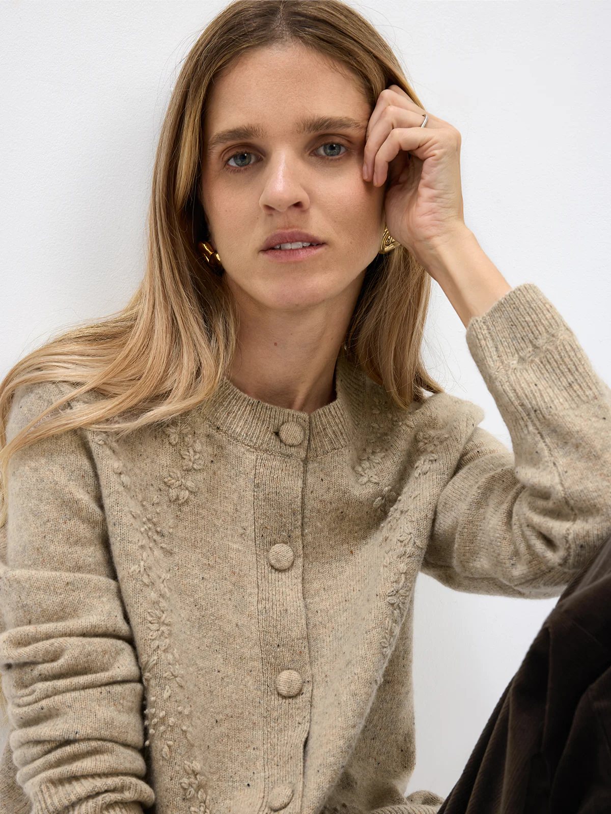 Front view of a model in a Light Brown Donegal knit cardigan with raised floral motifs, ribbed trim, and central buttons.