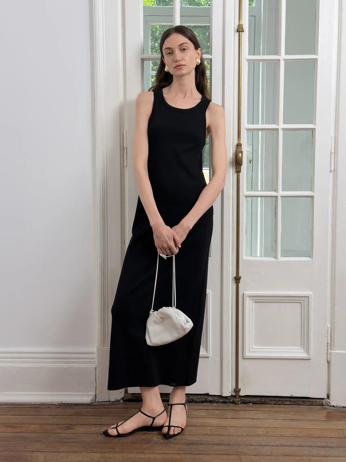 Black AUBREY fitted sleeveless tank dress with white drawstring bag and gold earrings