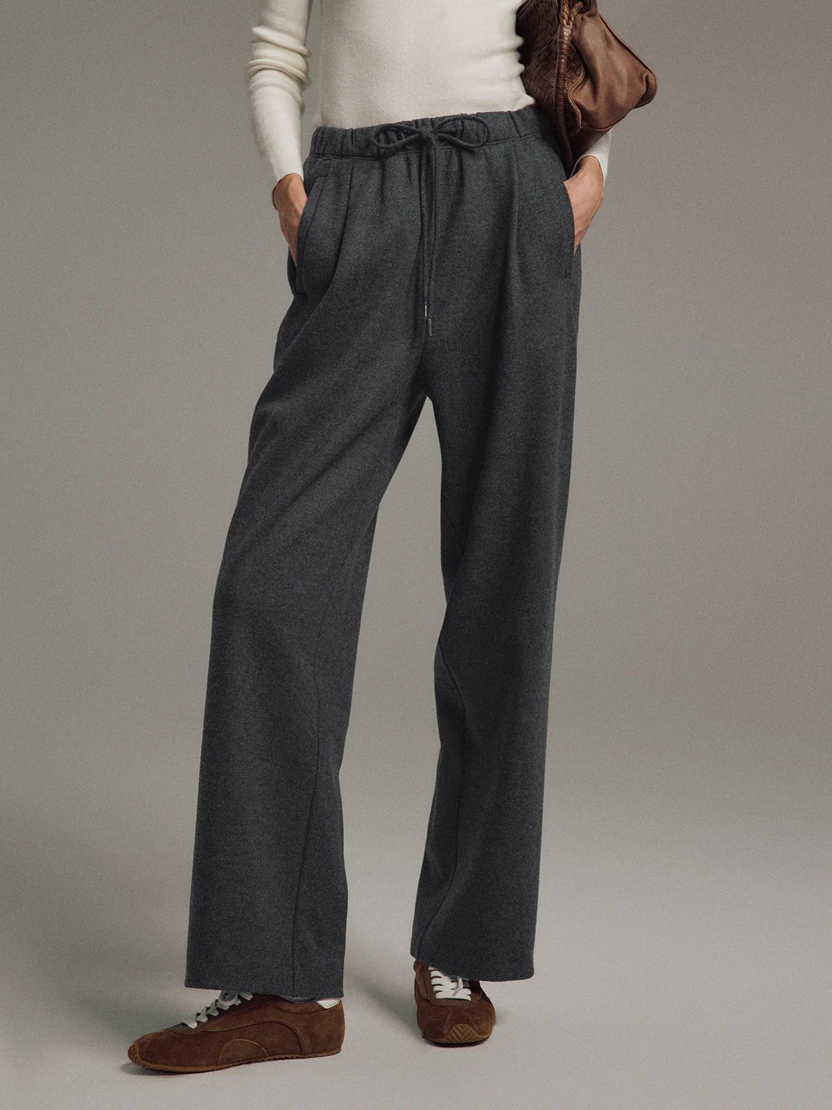 Model in Dark Gray straight trousers layered under a coat, hands in pockets, full-length side view.