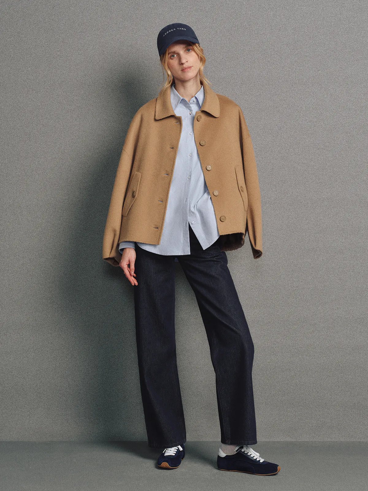 Front view of model wearing the Camel KELSEY short jacket with stand-up collar, button closure, and large patch pockets over dark trousers.