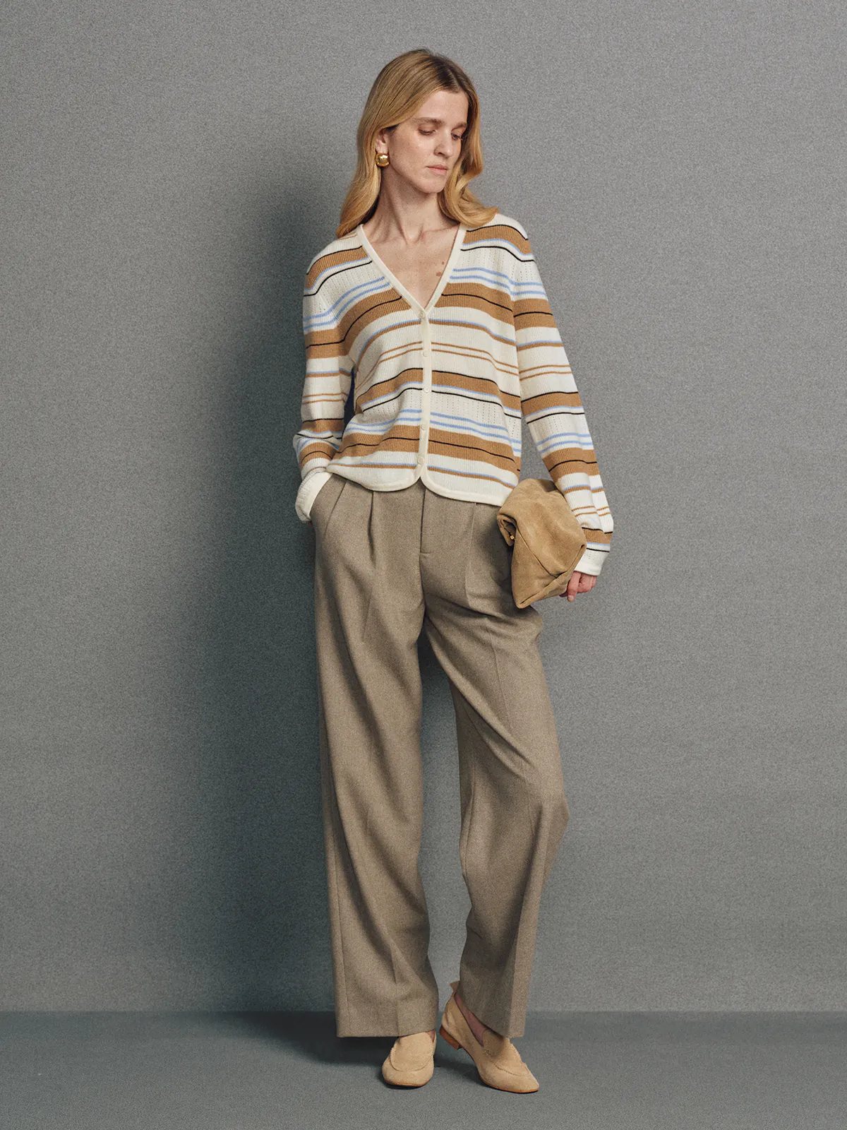 Model wearing the Camel multicolour stripe V-neck cardigan with trousers, holding a matching clutch in one hand.
