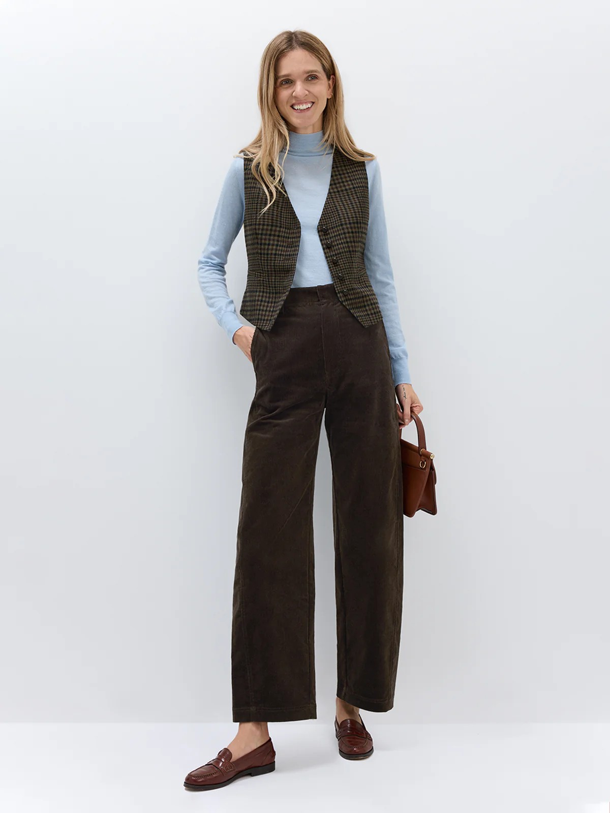 Front view of andreatang wool-blend brown check vest styled with light blue knit and wide-leg corduroy trousers