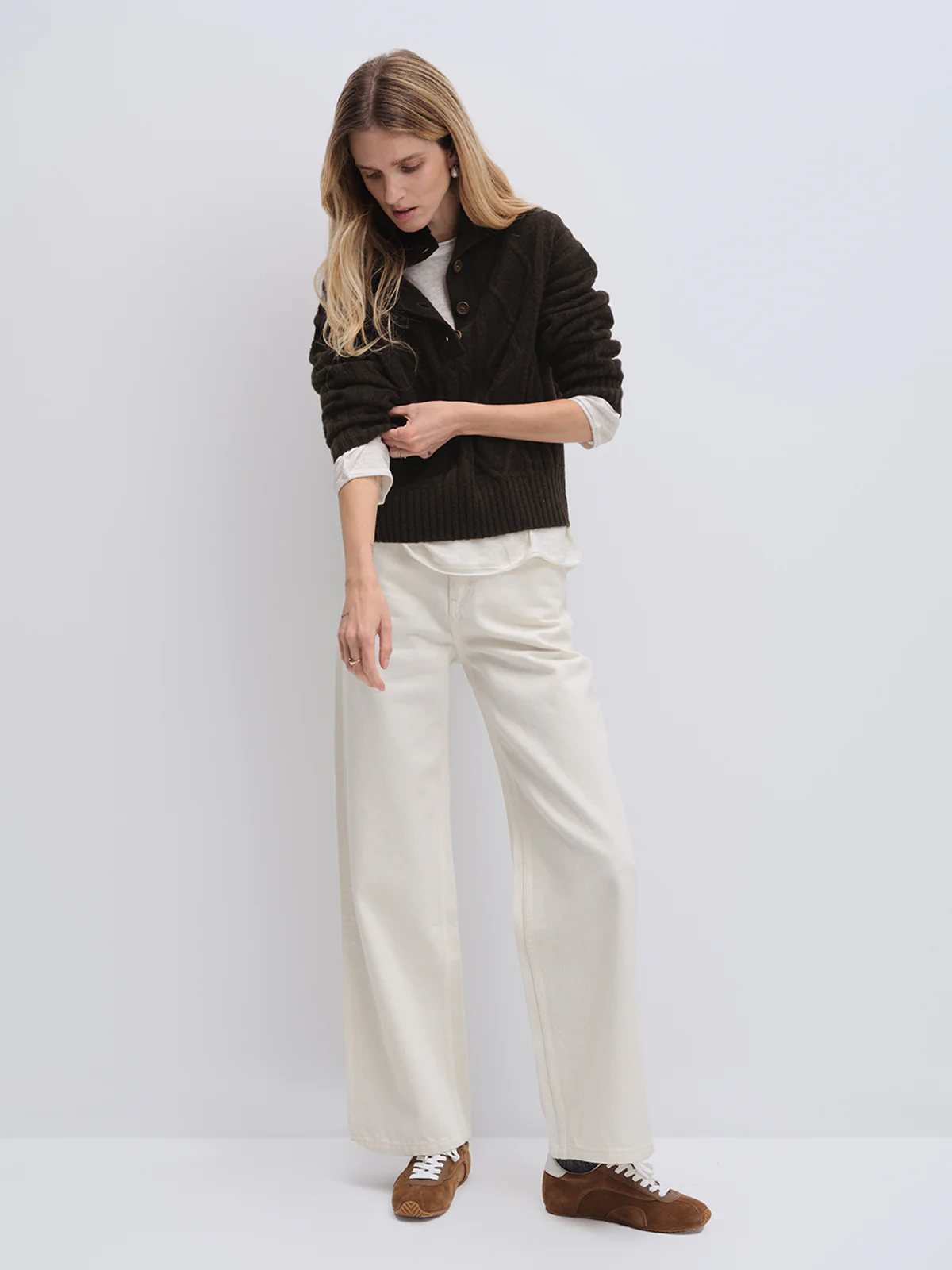 Model wearing andreatang cropped yak and wool sweater with wide-leg white trousers and sneakers