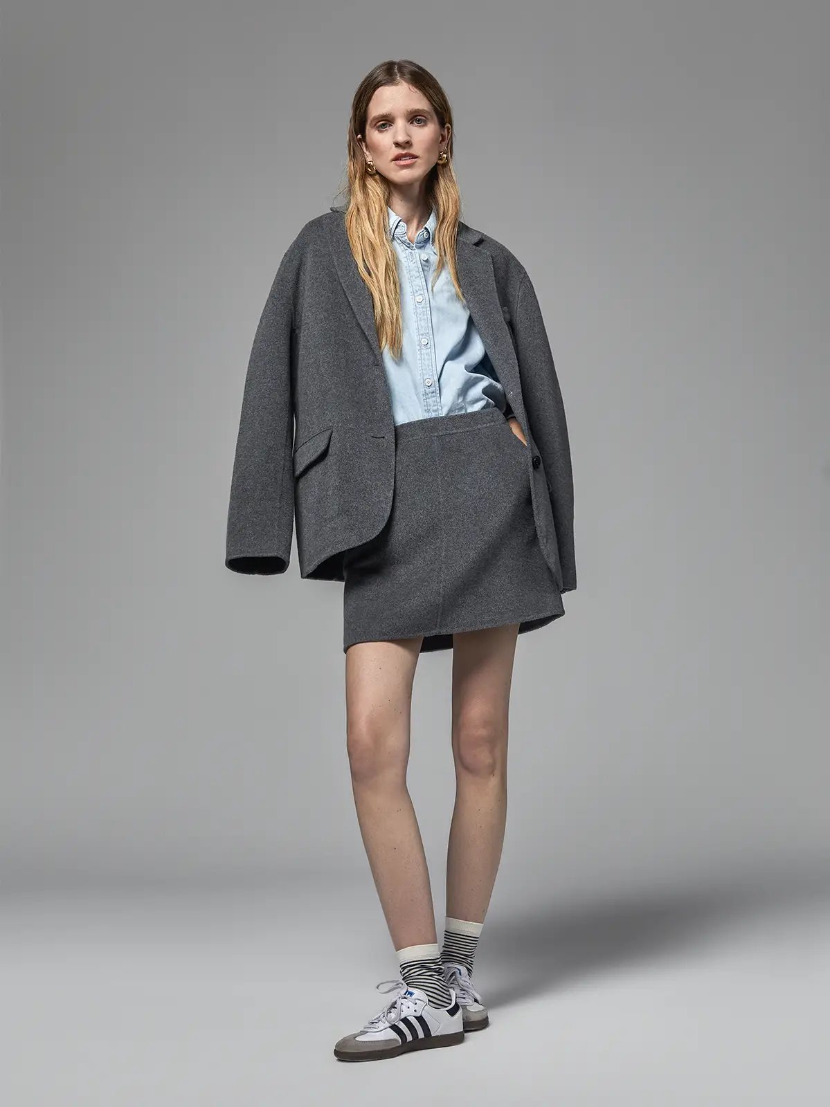 Mixed Gray short A-line skirt paired with an oversized gray blazer and light shirt.