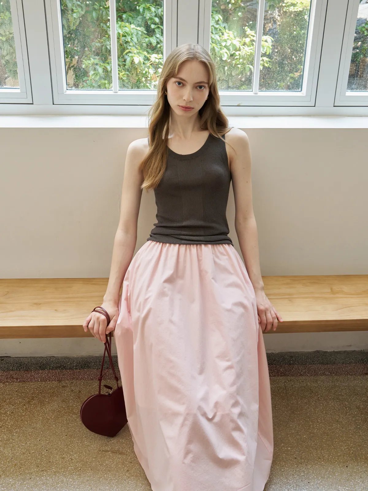 Model in charcoal MEADOW Textured Knit Tank Top with blush pink maxi skirt and heart-shaped leather bag, indoor window setting