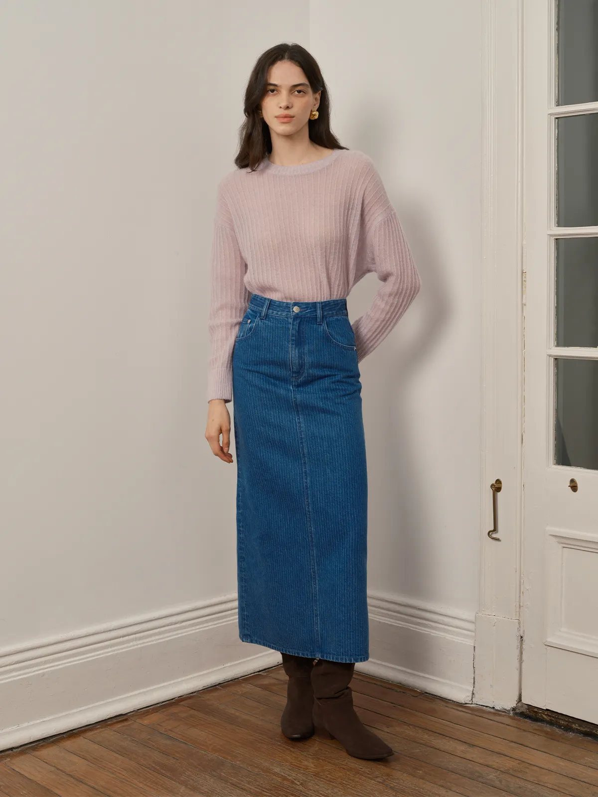 Front full-body shot of model wearing BRYCE striped denim maxi skirt with lavender ribbed sweater and brown suede boots against white wall