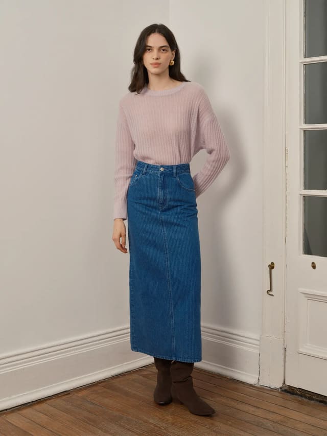 Front full-body shot of model wearing BRYCE striped denim maxi skirt with lavender ribbed sweater and brown suede boots against white wall