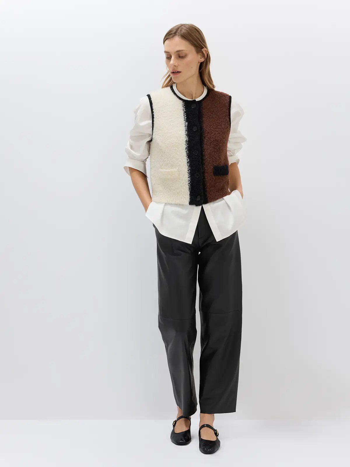 Front-facing black sheepskin leather casual pants with pleats, worn with a black cropped jacket, turtleneck, and pointed heels.