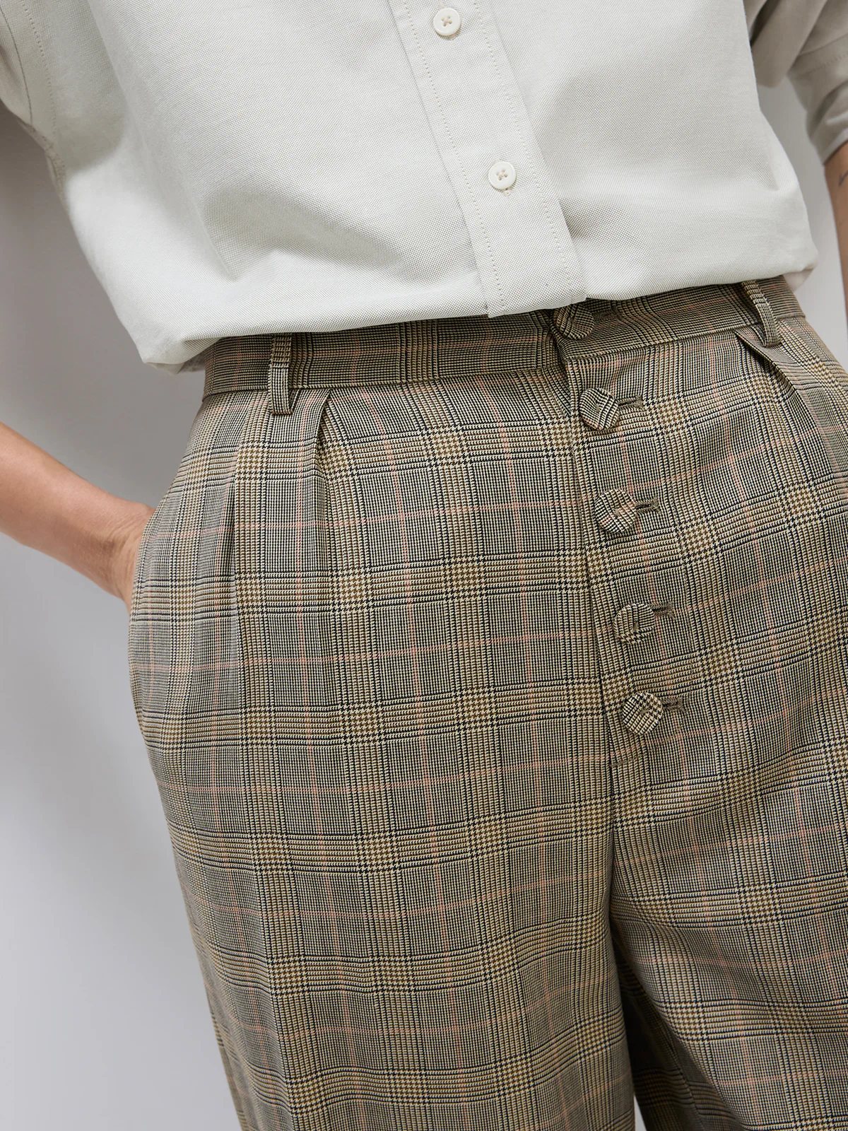 Side view of wide-leg Prince of Wales check trousers with pleated front and four-button waistband.