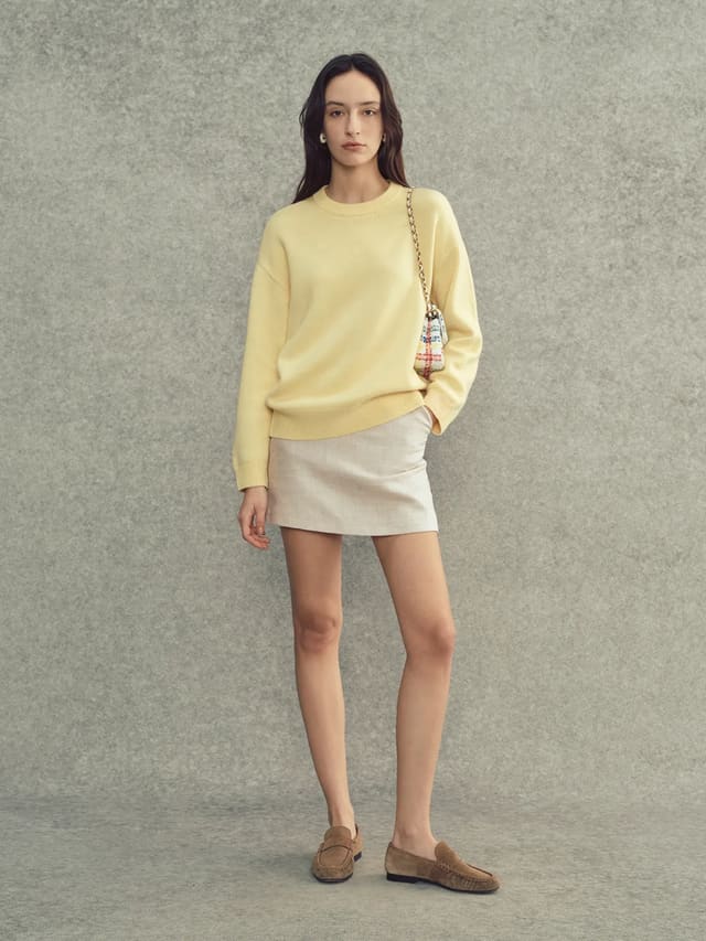 Andrea Tang JILL cashmere wool crew neck jumper in pale yellow, styled with beige mini skirt and suede loafers, front full-body shot