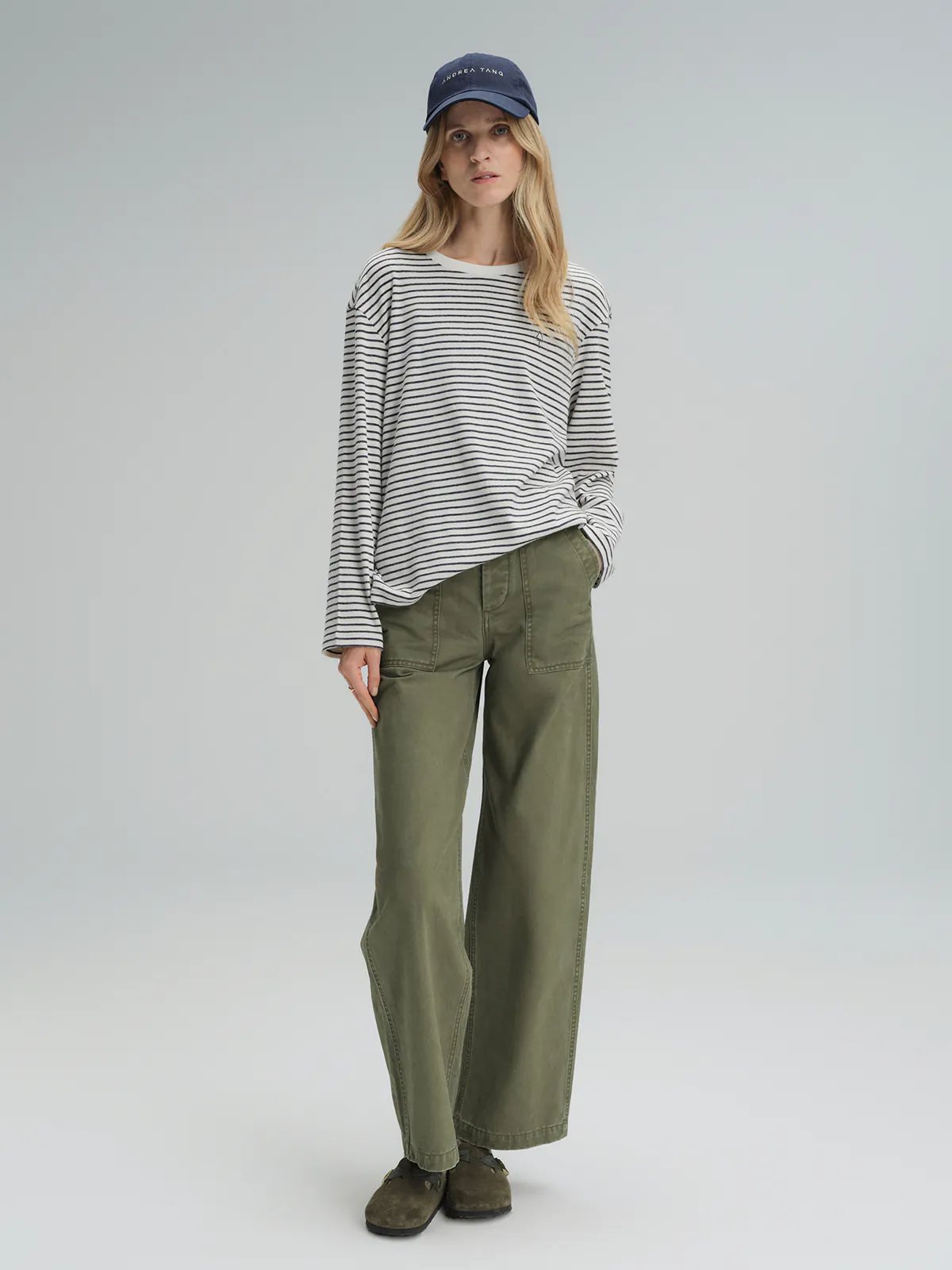Front view of model in khaki cotton utility trousers with relaxed wide-leg fit and front patch pockets.