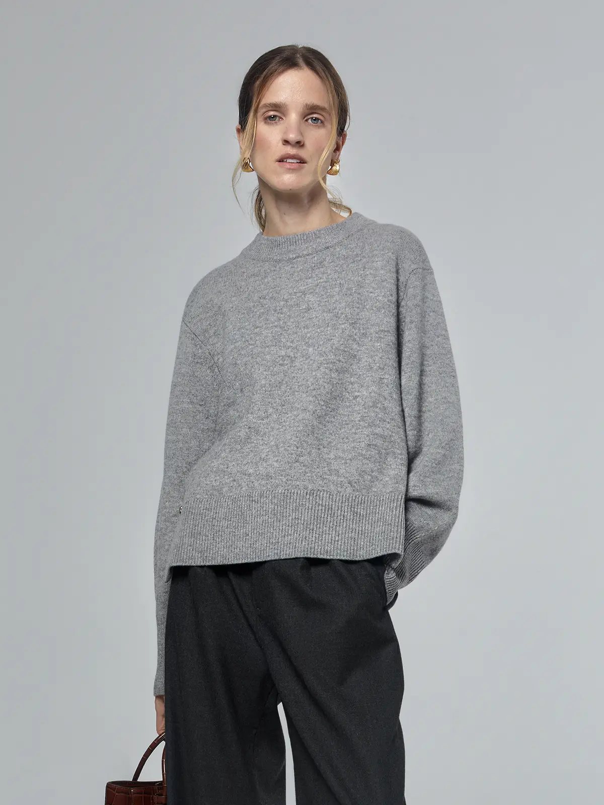 Front view of a grey merino wool sweater with metal buttons, ribbed hem, and relaxed fit.