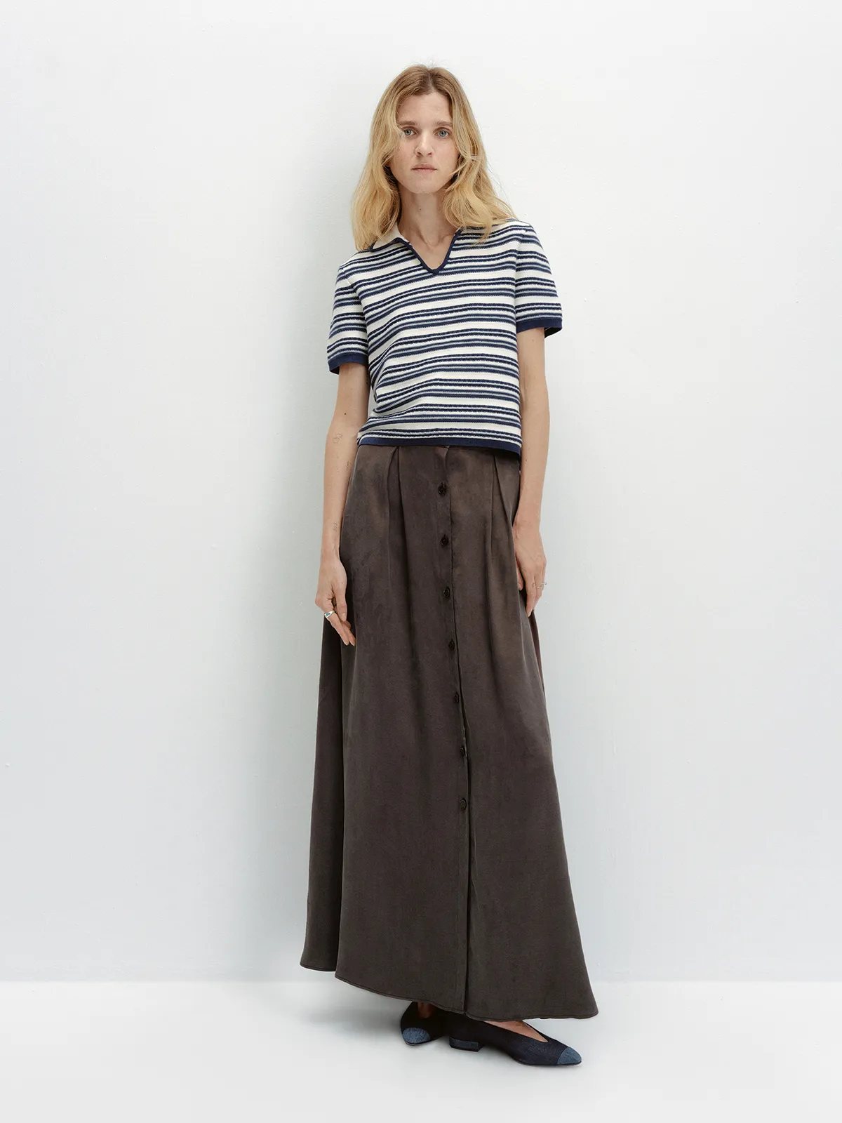 Full-length front view of ANGELINA polo with brown button-front maxi skirt and two-tone flats