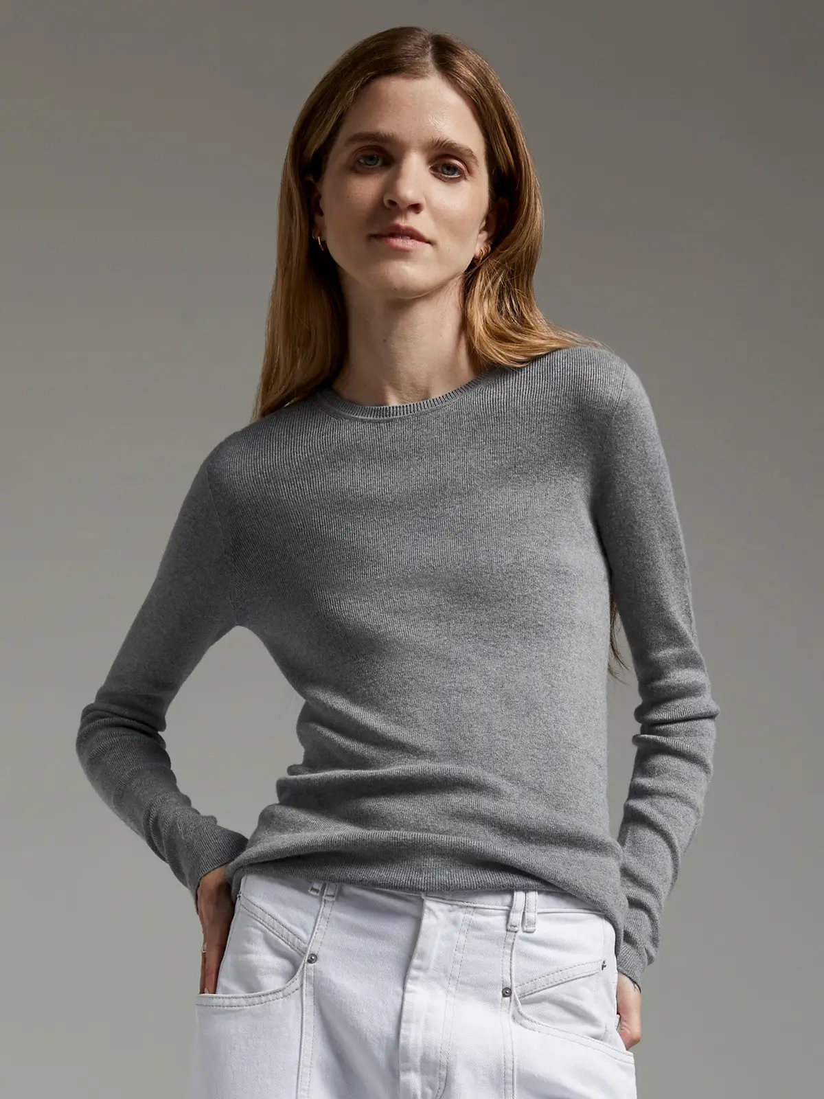 Front view of a grey slim fit long-sleeve knit top with crew neck, worn with jeans.