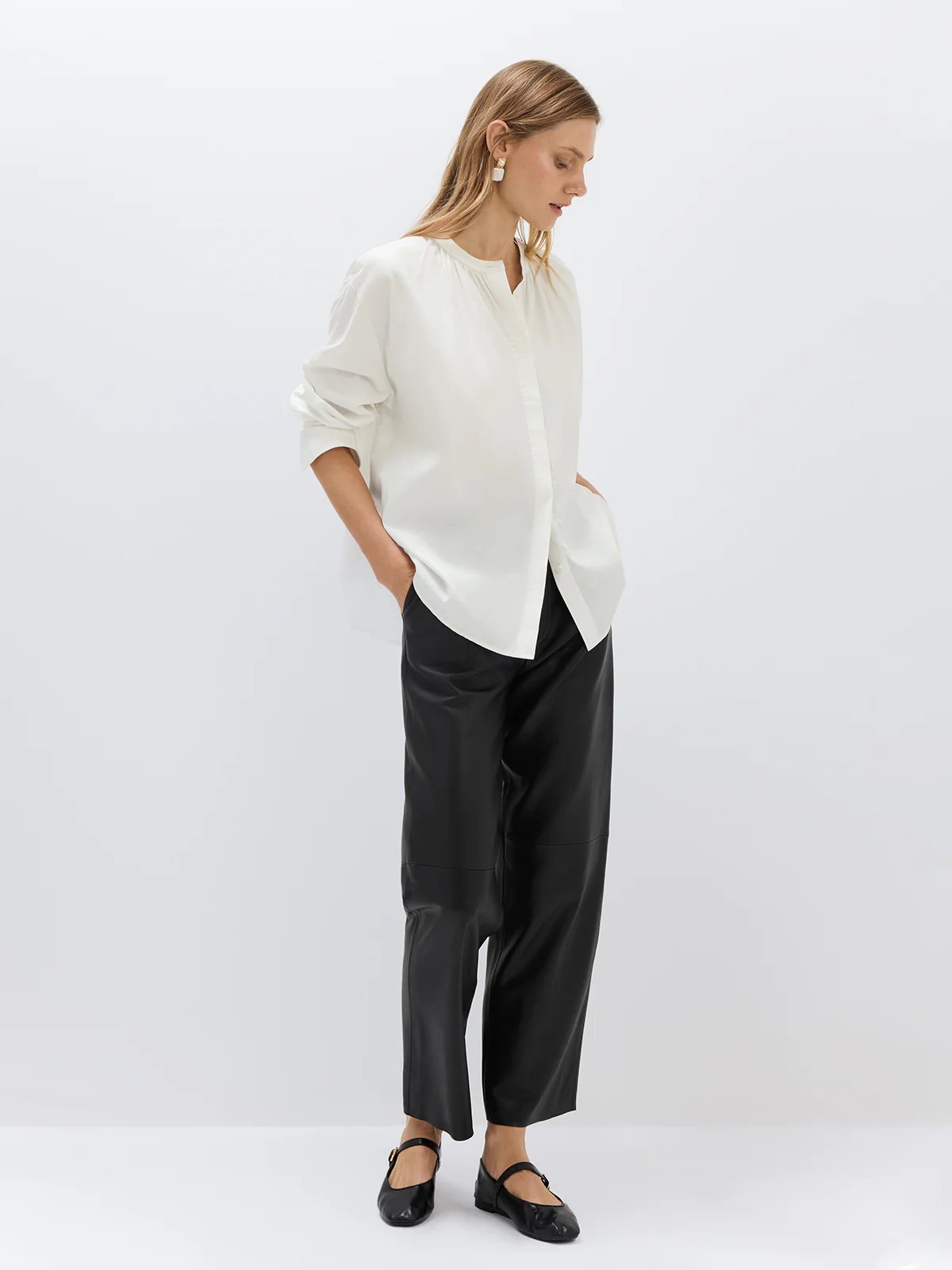 White textured blouse with gathered neckline and cuffed sleeves, worn with trousers in a side stance.