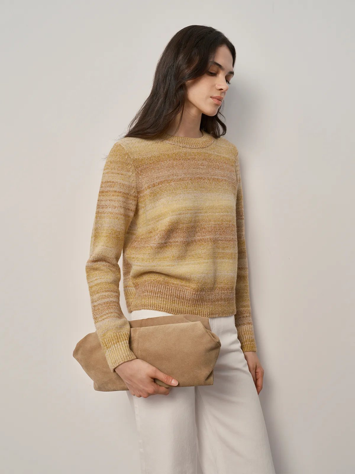 Side profile of model in TANYA Gradient Stripe Knit Vest holding beige suede clutch