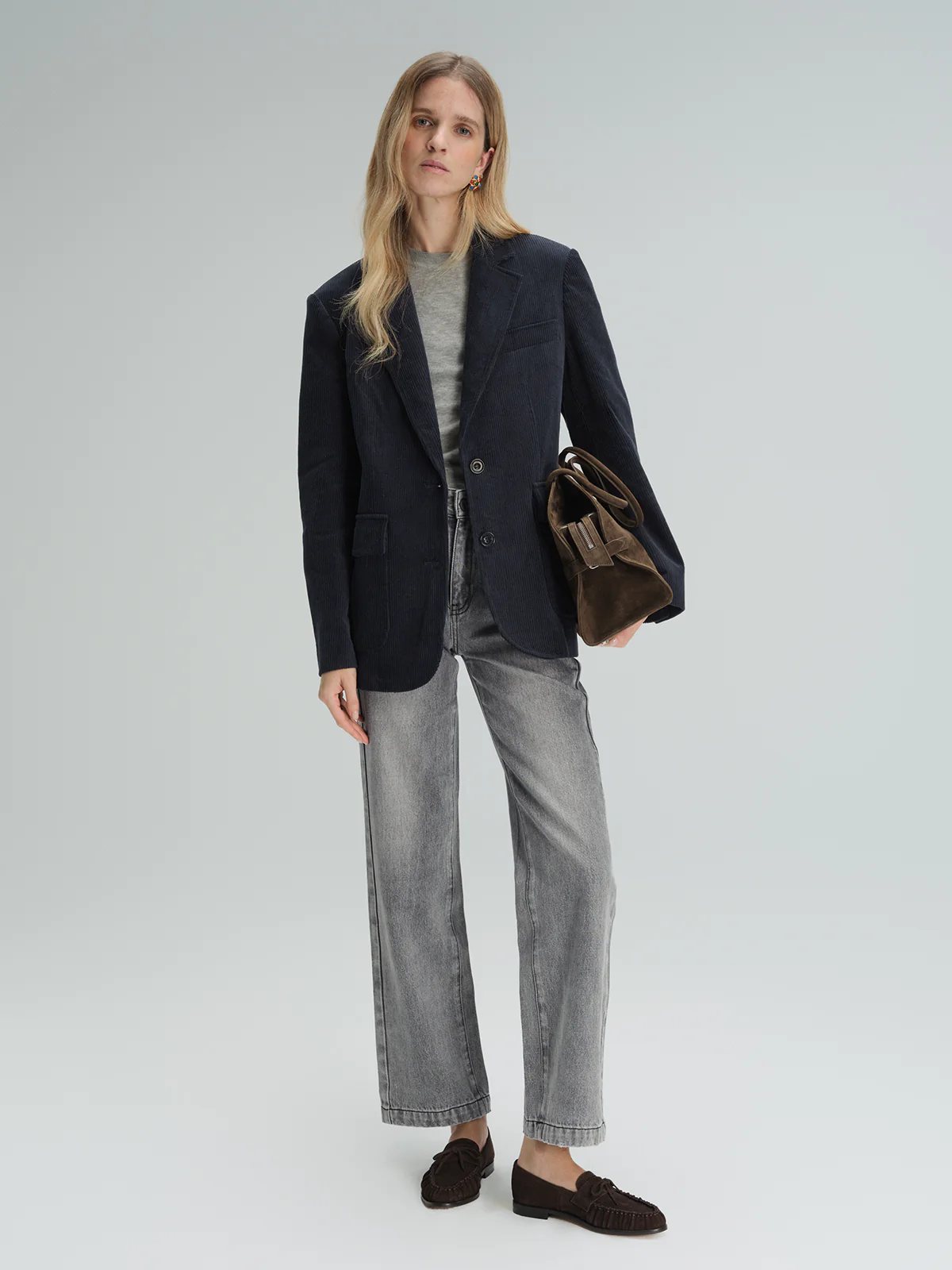 Model wearing the navy corduroy tailored blazer over a light shirt with trousers and arms crossed.