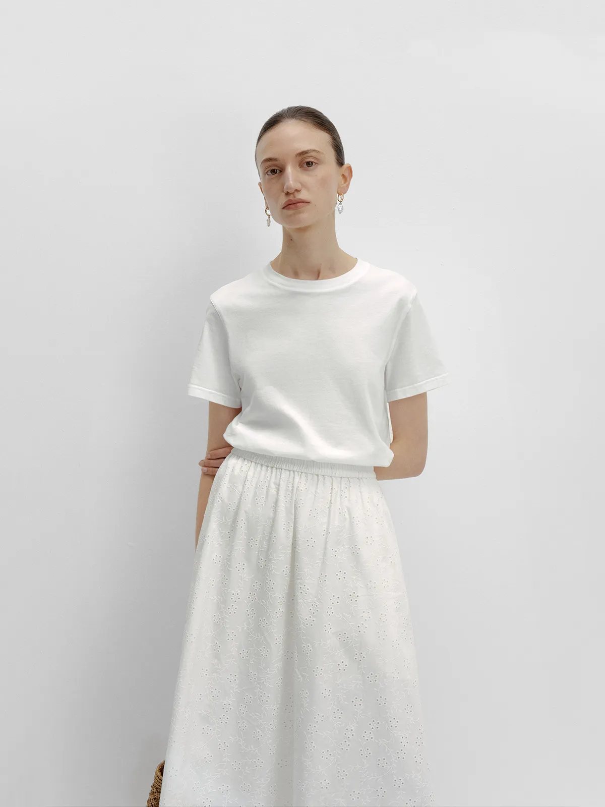 Model in white relaxed t-shirt with white eyelet floral midi skirt, soft summer styling by andreatang