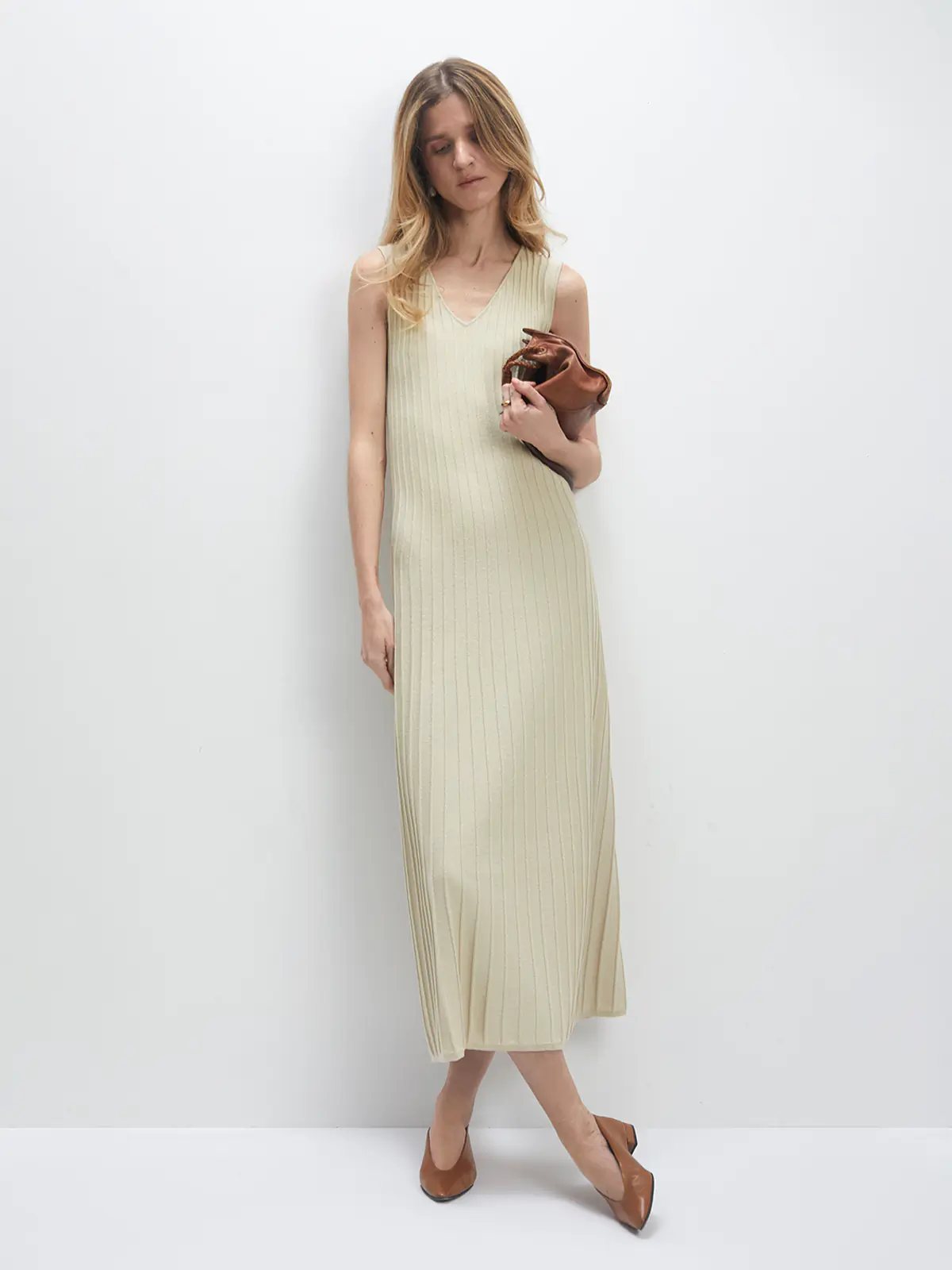 Model wears the Light Lime Green JOCELYN V-neck sleeveless knit dress with vertical ribbing, holding a clutch.