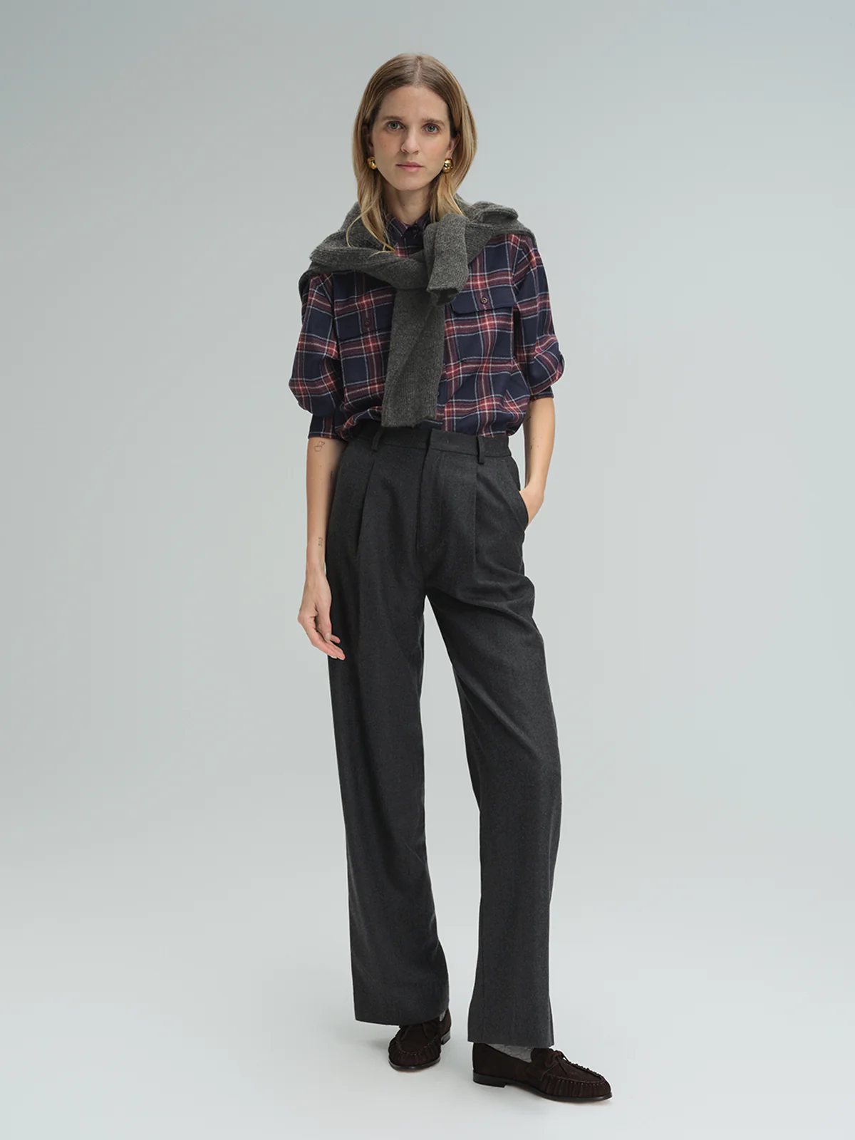 Model wearing andreatang pure wool flannel straight-leg trousers in dark grey with plaid shirt and knit over shoulders