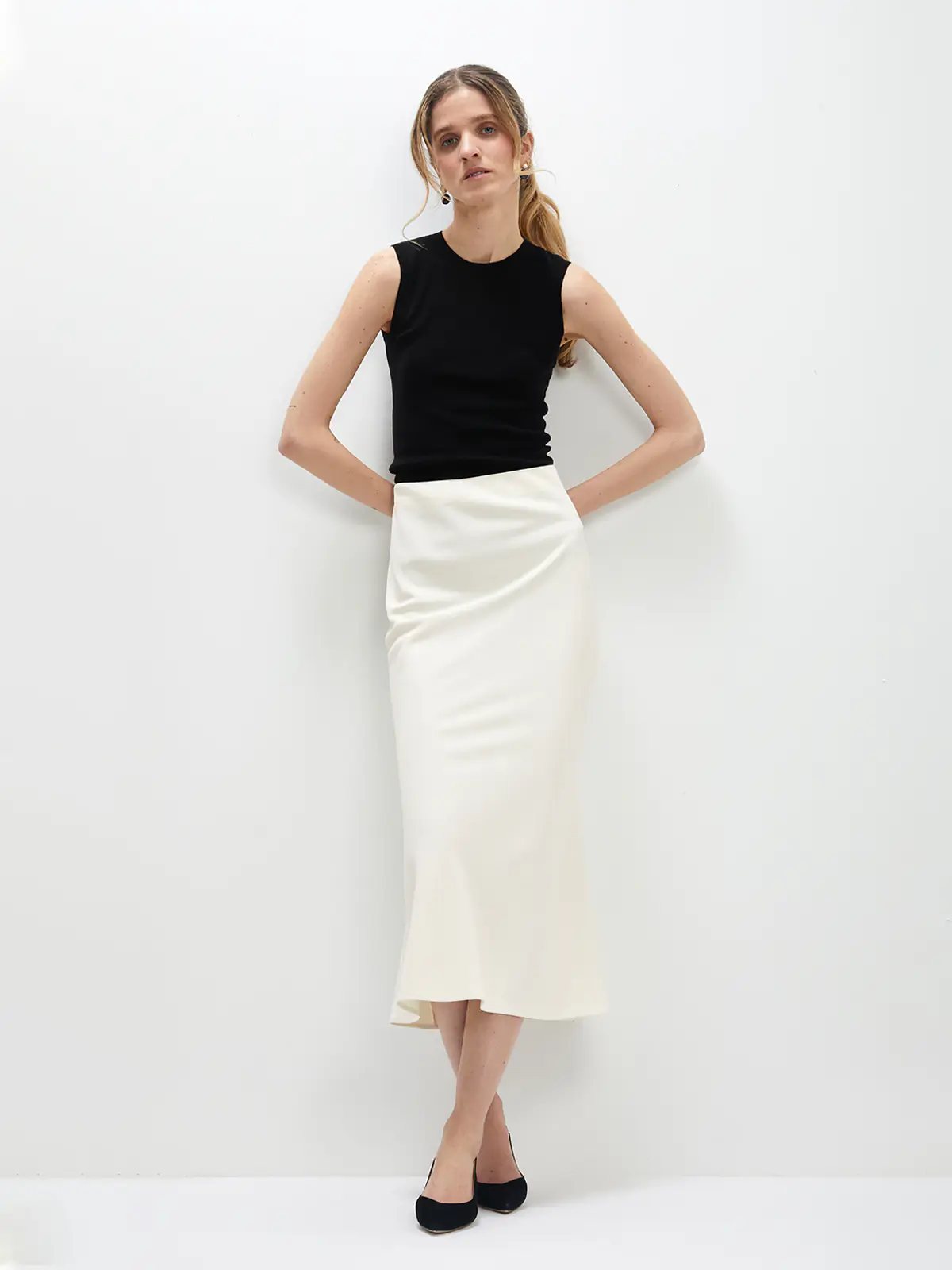 Model in a white acetate mermaid skirt paired with a sleeveless top and shoes, front pose.