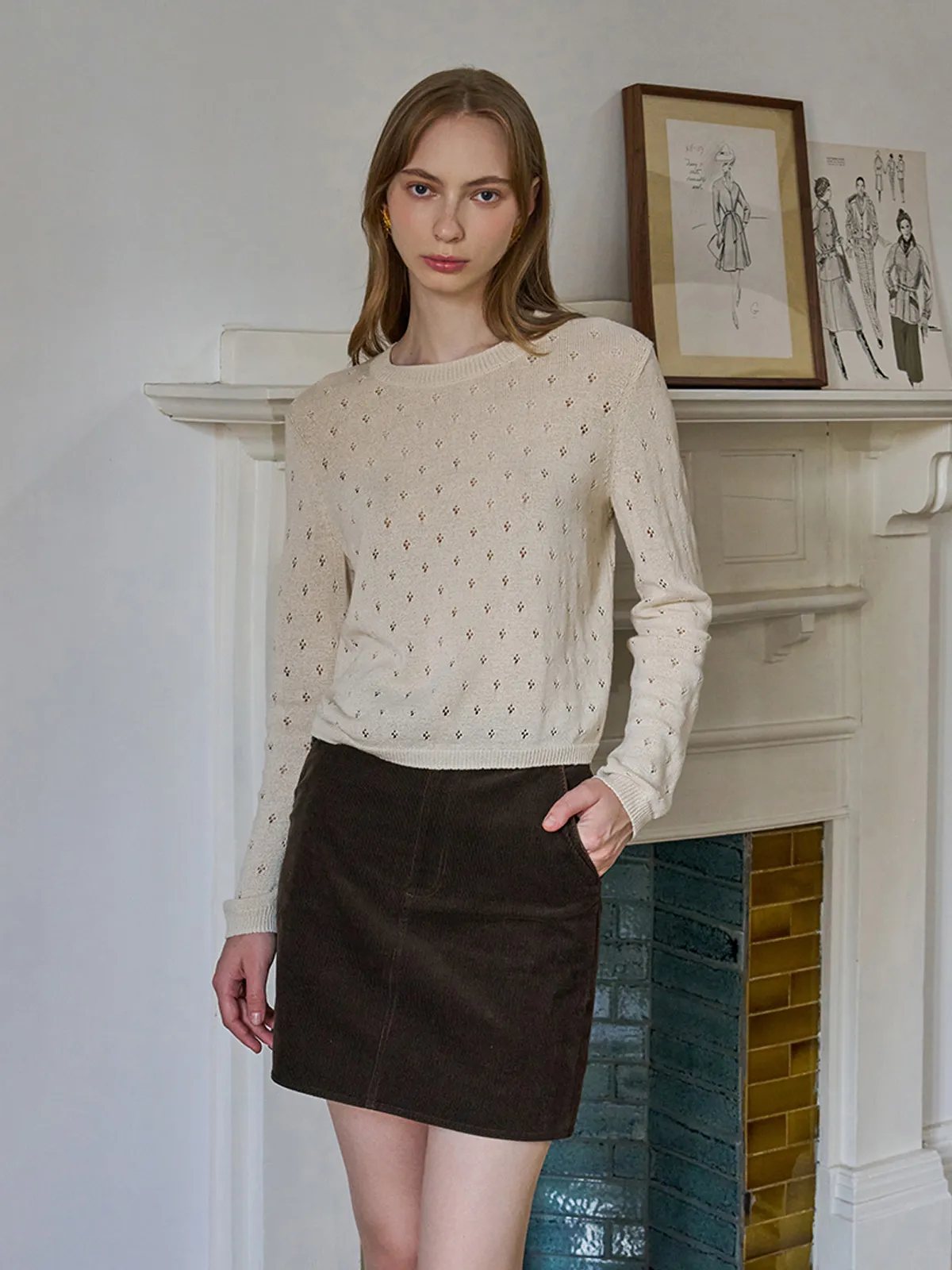 Front view of model in KIANA knit top with brown corduroy mini skirt and gold earrings