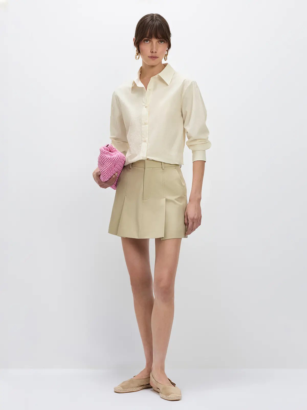 Front view of the Beige NAOMI shirt with rolled sleeves, worn over a beige skirt with one hand in pocket.