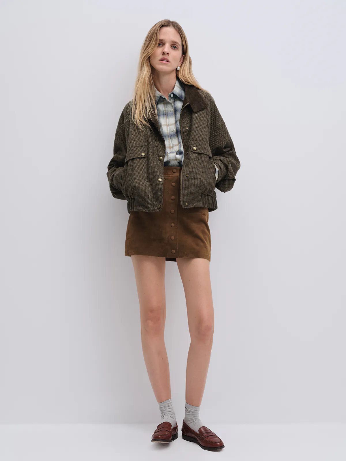 Front-facing model in the Brown houndstooth corduroy reversible jacket with hands in pockets, over a denim shirt and jeans.