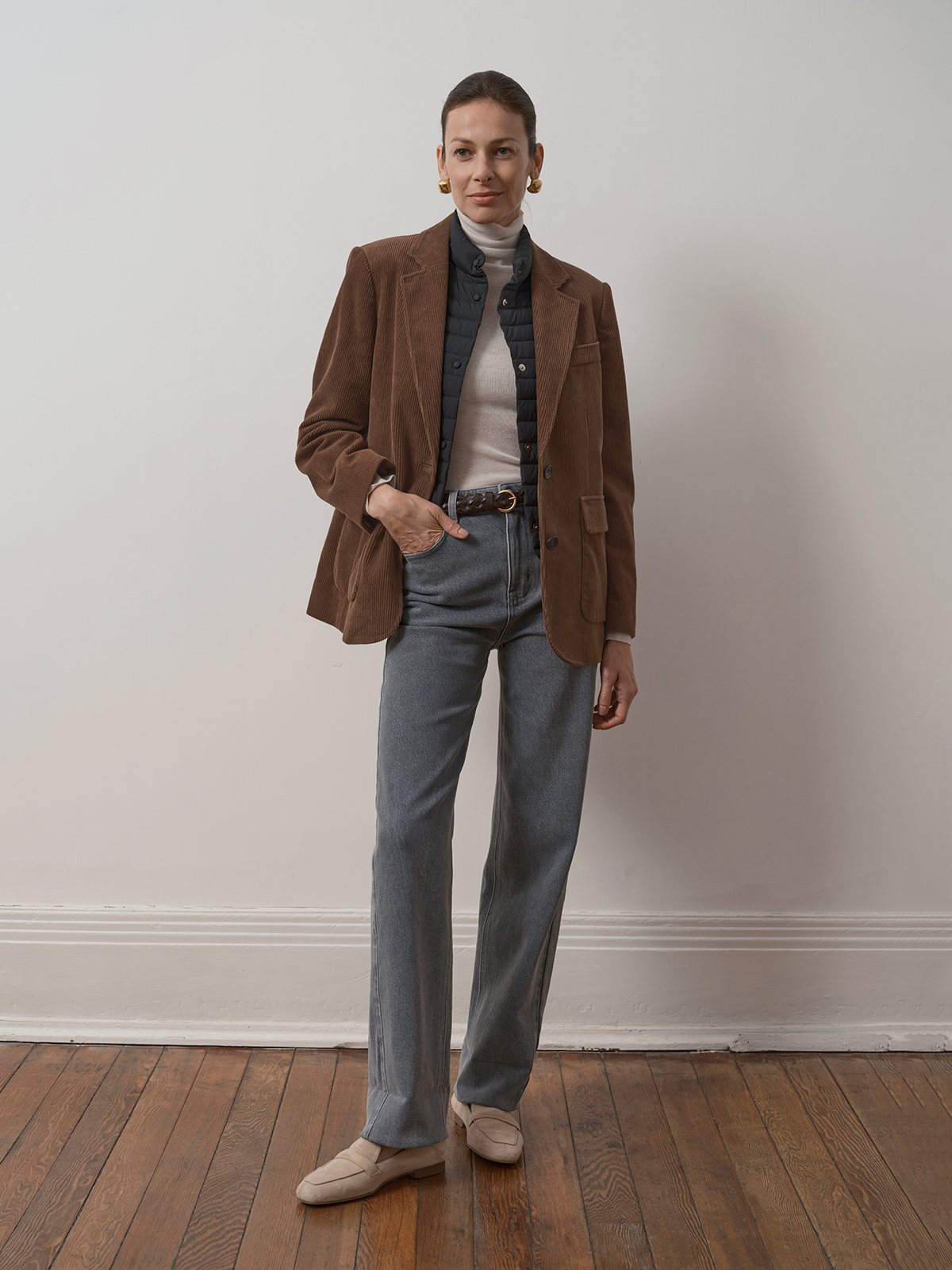Full-length model pose in KIMBERLEY brown corduroy blazer with quilted vest, turtleneck, and grey trousers
